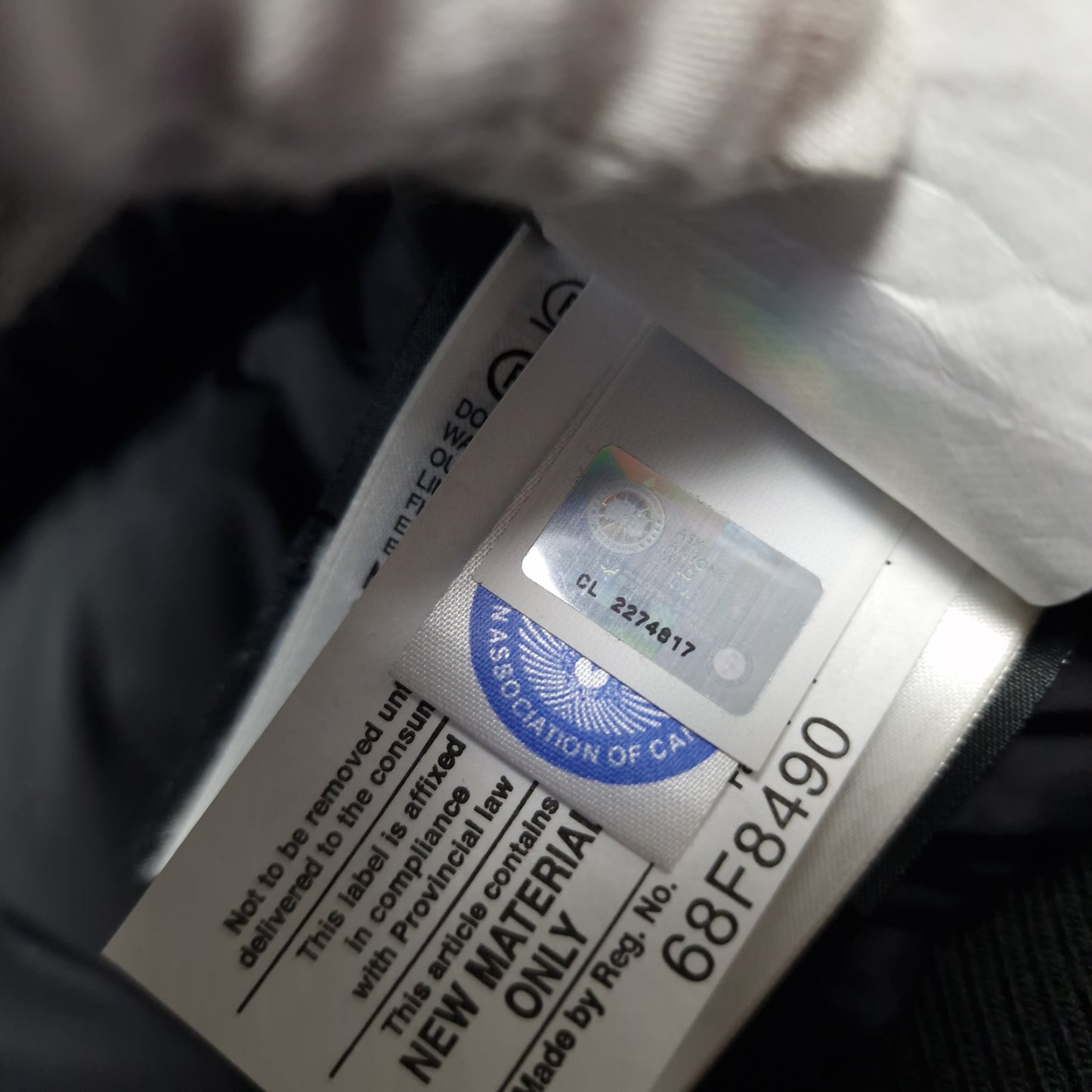 Close-up of Canada Goose authenticity hologram on Chilliwack Bomber 7950M, verification label confirming genuine men's Small black luxury bomber jacket