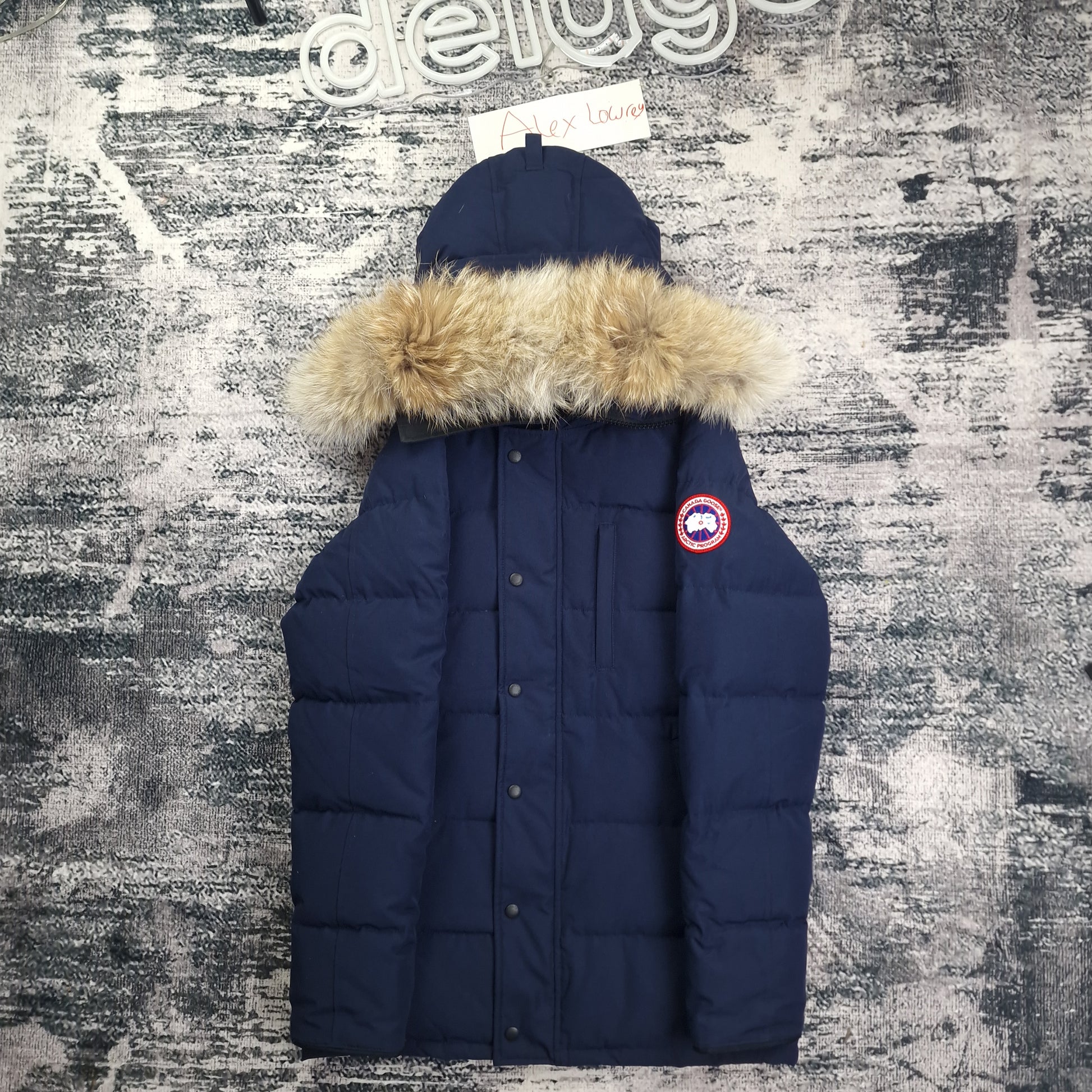Front flat lay of Canada Goose Carson Parka 3805MA men's medium with coyote fur hood trim, chest pockets, and Arctic Program badge