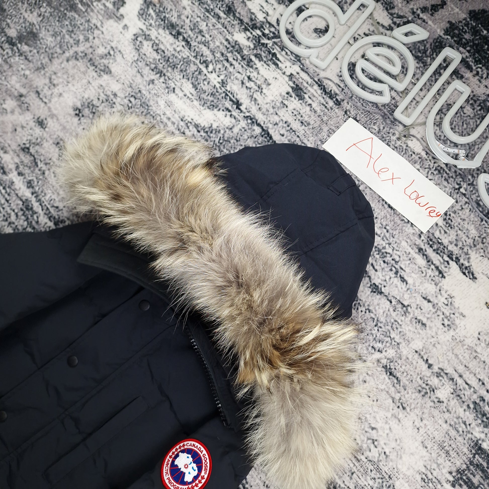 Close-up flat lay of Canada Goose Carson Parka 3805MA showing luxurious coyote fur hood trim and Arctic Program disc badge