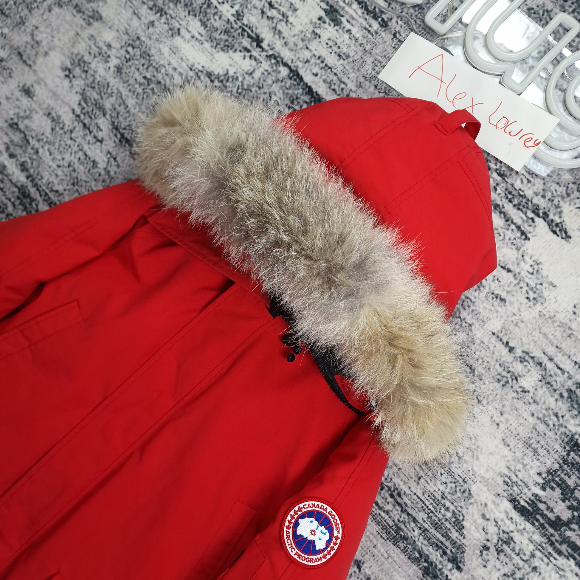 Close-up detail shot of Canada Goose Chilliwack red bomber jacket hood showing genuine coyote fur trim and Arctic disc patch