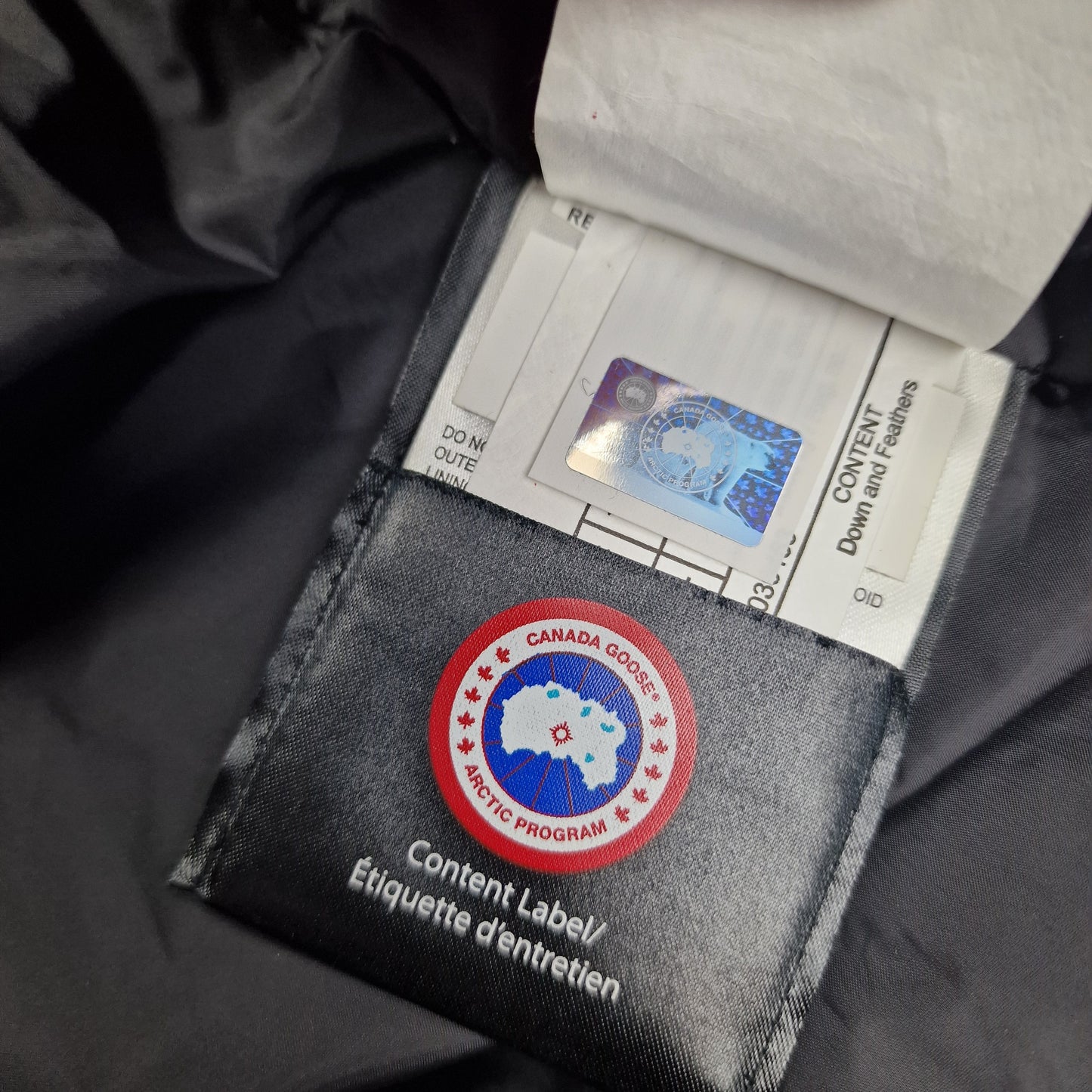 Authentic Canada Goose hologram security tag with down content label showing genuine Lorette Parka verification and quality certification
Retry