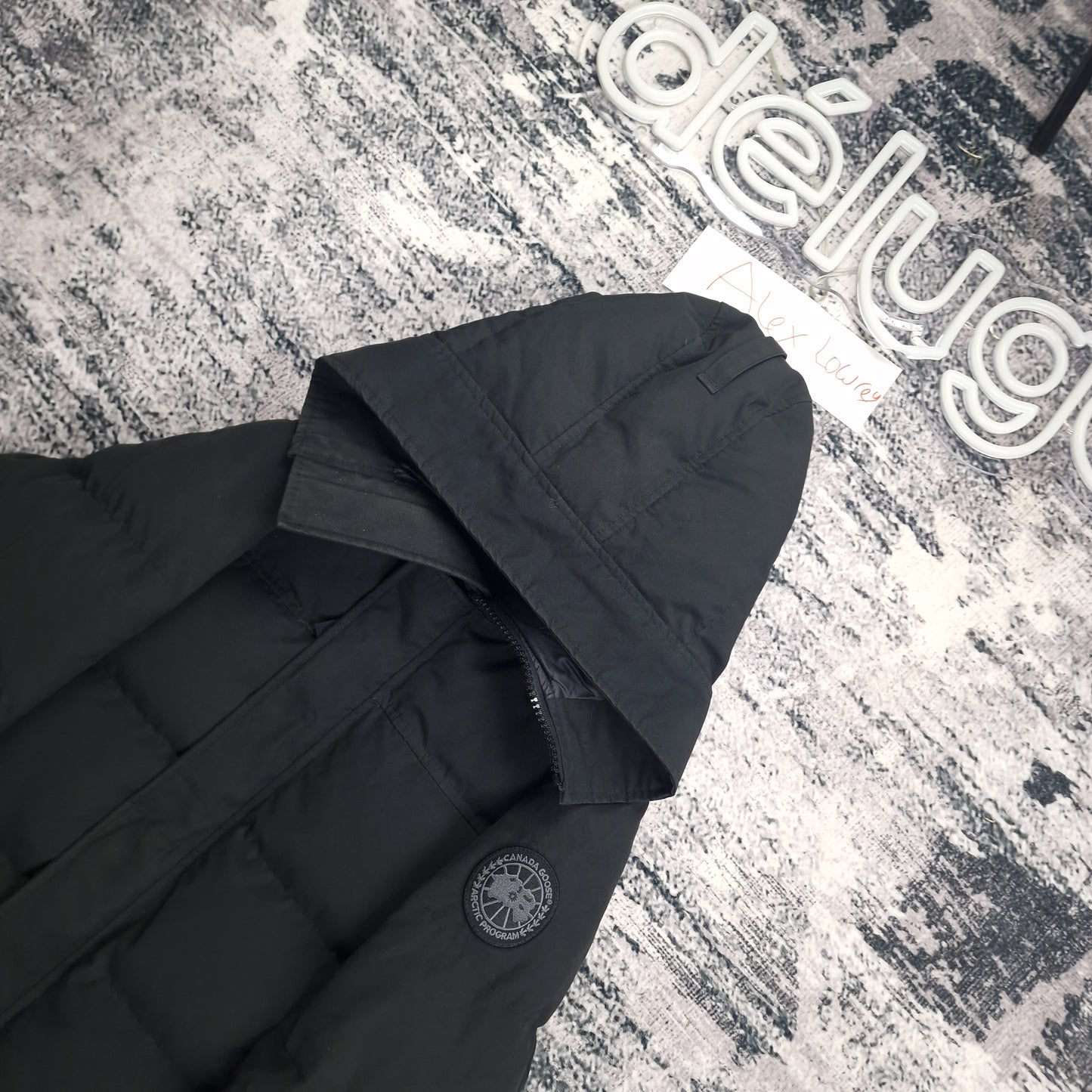 Close-up flat lay of Canada Goose Macmillan Black Label Parka showing hood construction and tonal black Arctic Program badge