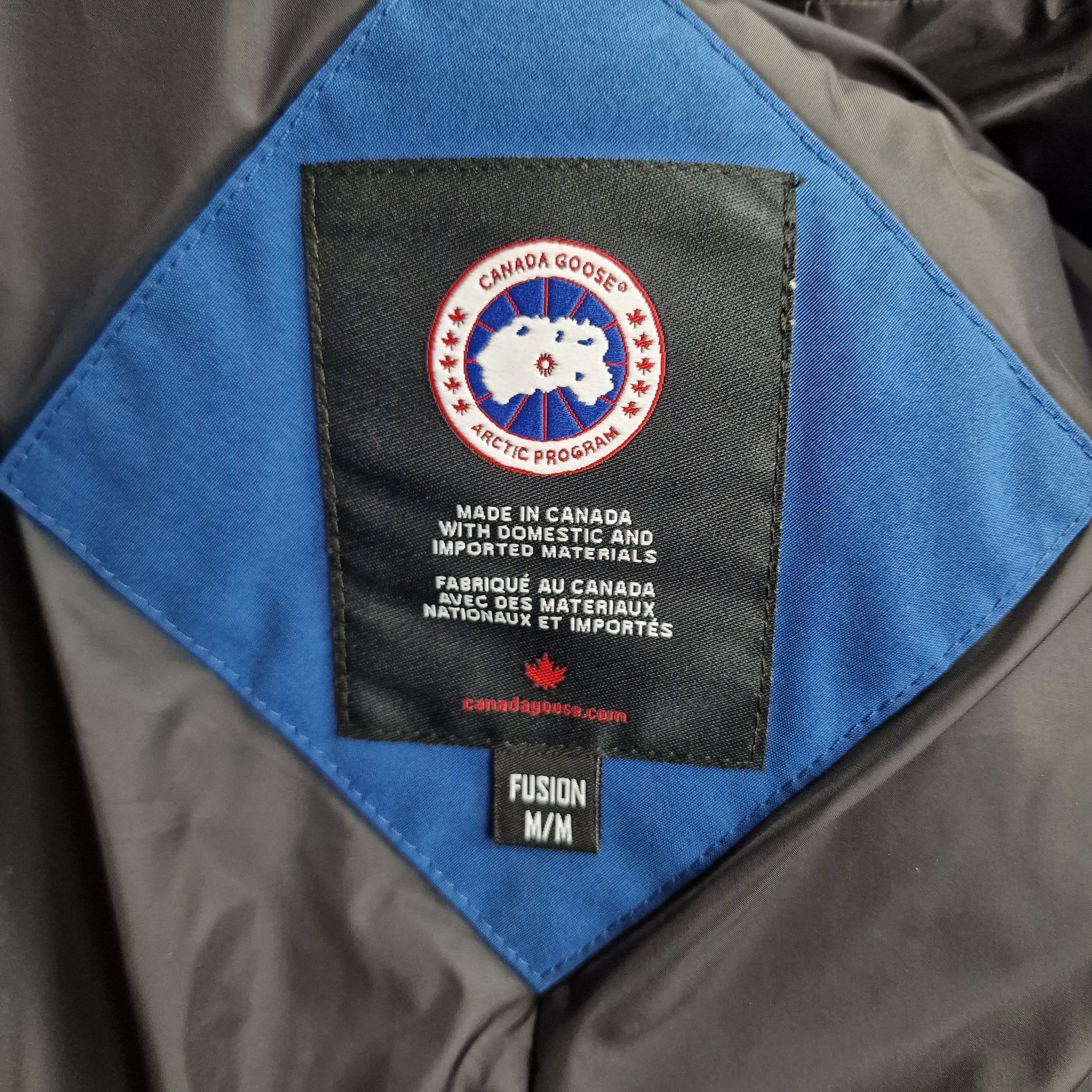 Close-up of authentic Canada Goose interior label showing Fusion fit, size M/M, Arctic Program badge, and Made in Canada certification