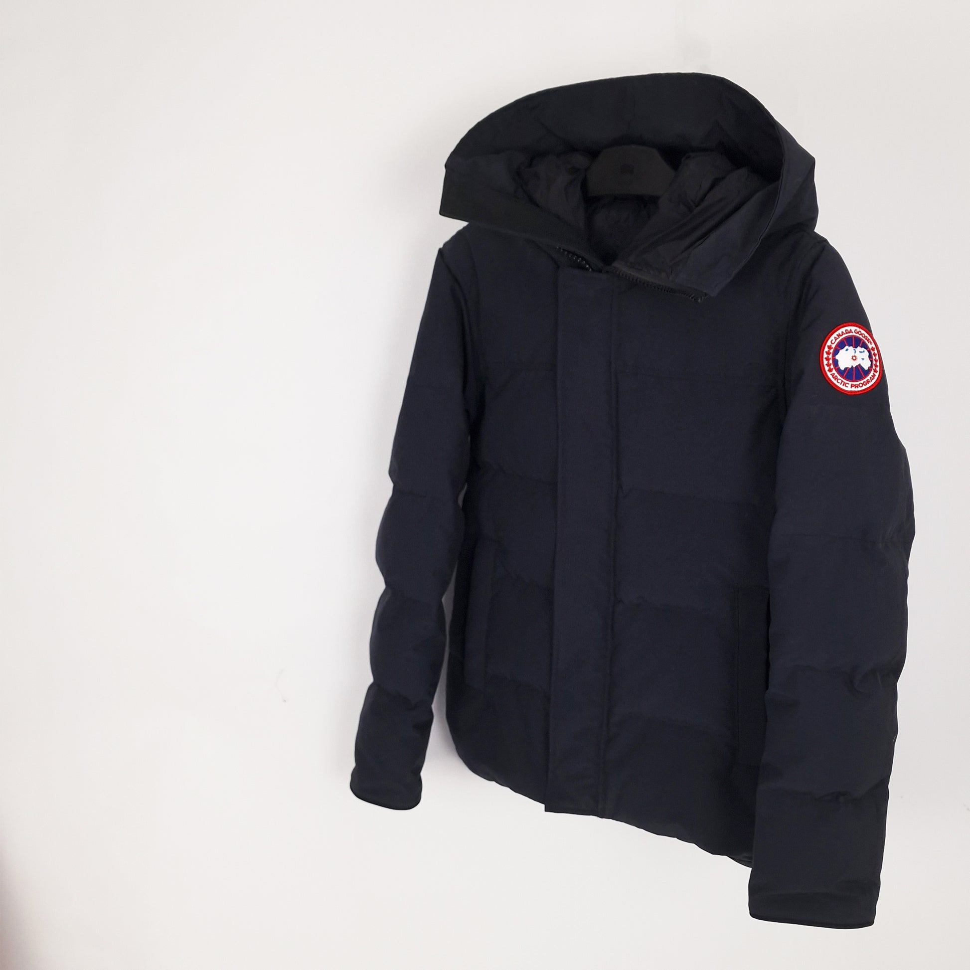 Angled view of navy Canada Goose Macmillan Parka men's extra small showing Arctic Program badge and ribbed cuffs