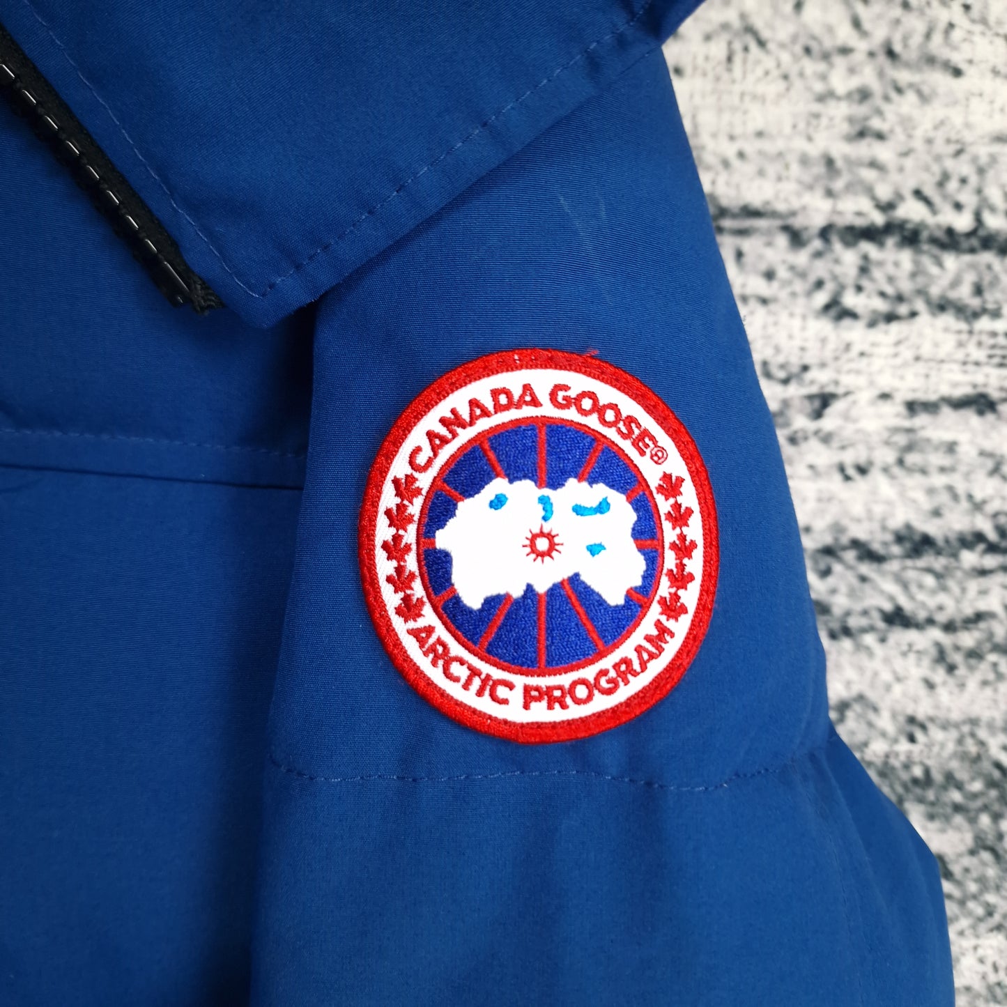 Detailed close-up of authentic Canada Goose Arctic Program patch on Northern Night blue Macmillan Parka men's medium sleeve
