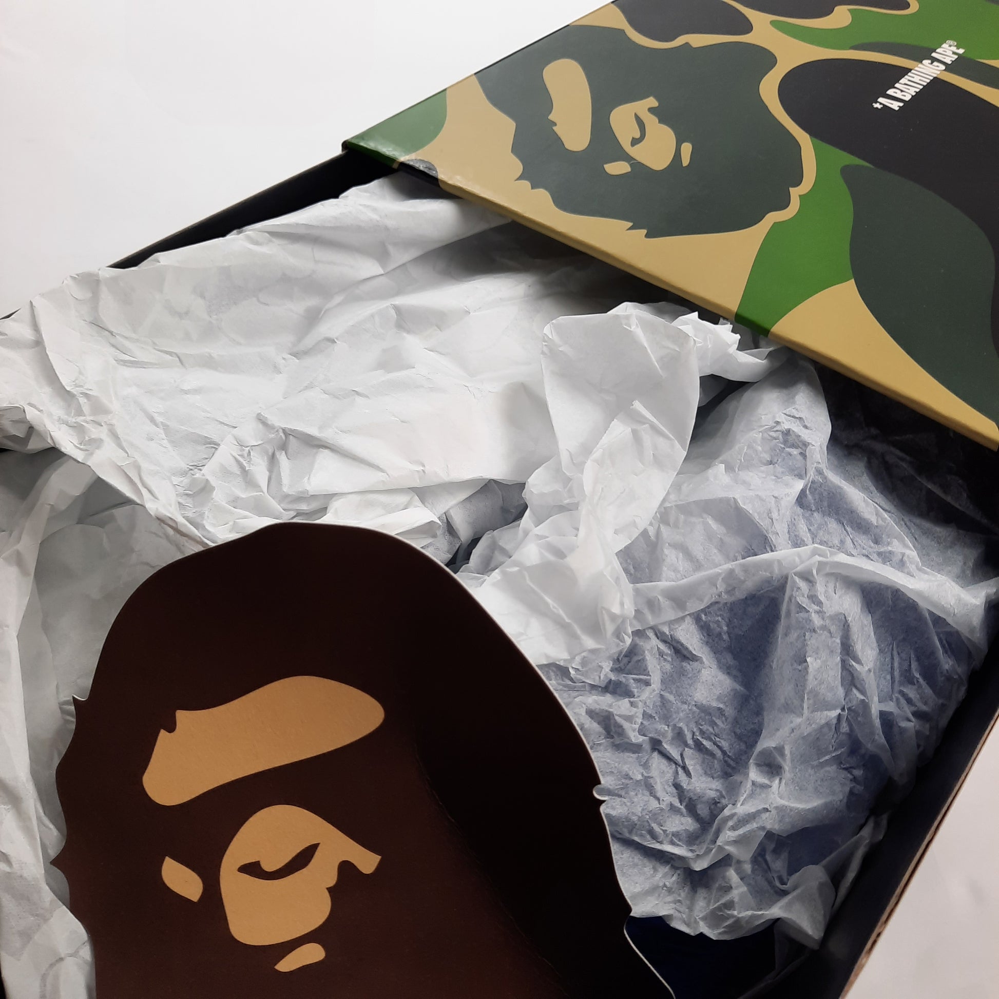 Opened A Bathing Ape Bapesta box showing tissue paper wrapping and ape head logo, authentic sneaker packaging