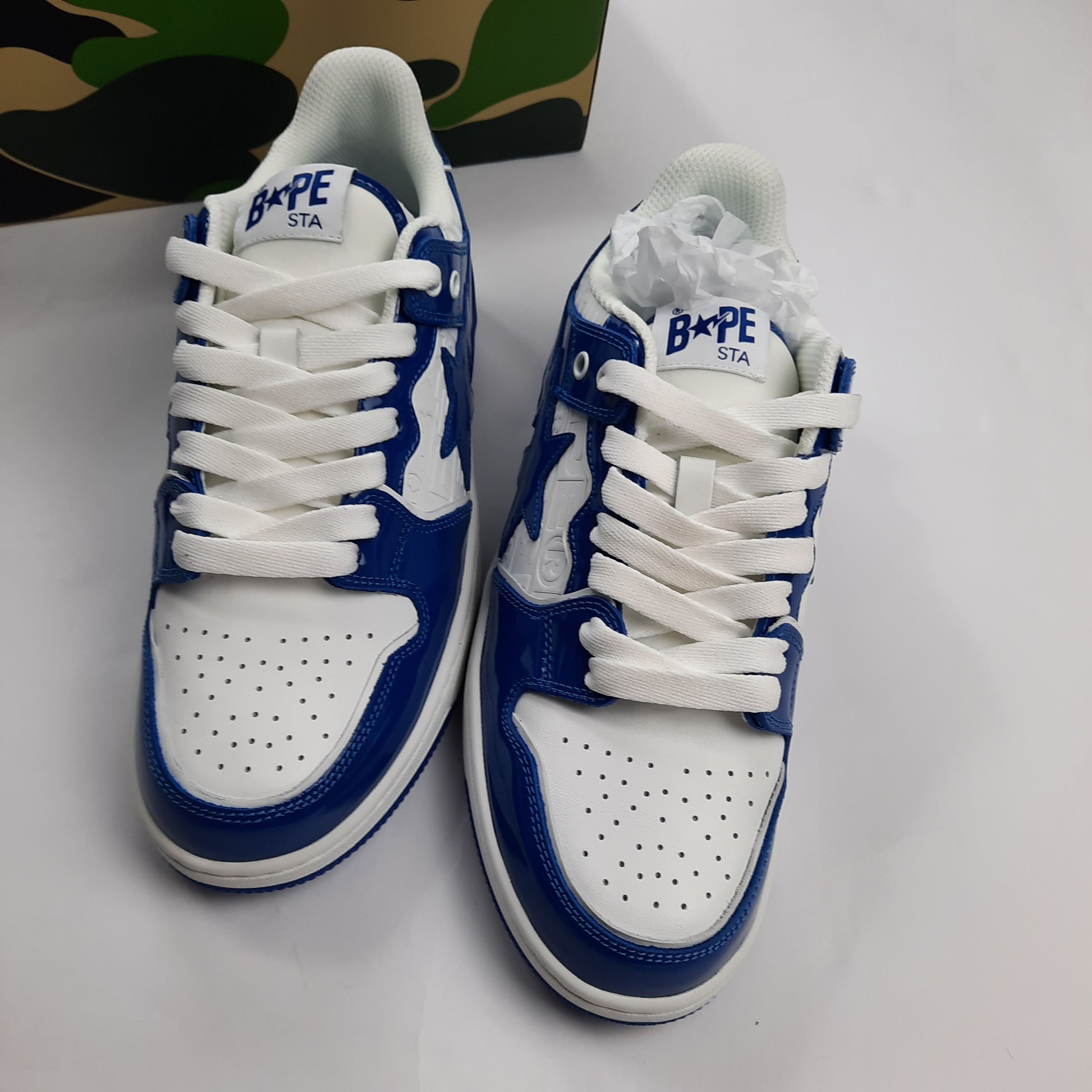 Top down view of A Bathing Ape Bapesta sneakers in blue and white, showing white laces and perforated toe box
