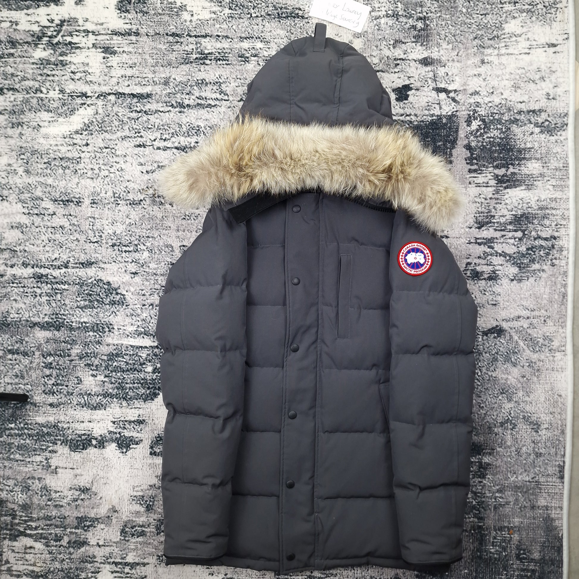 Front view of men's Canada Goose Carson Parka 3805M Small in Graphite grey with coyote fur-trimmed hood, luxury winter coat photographed on styled background