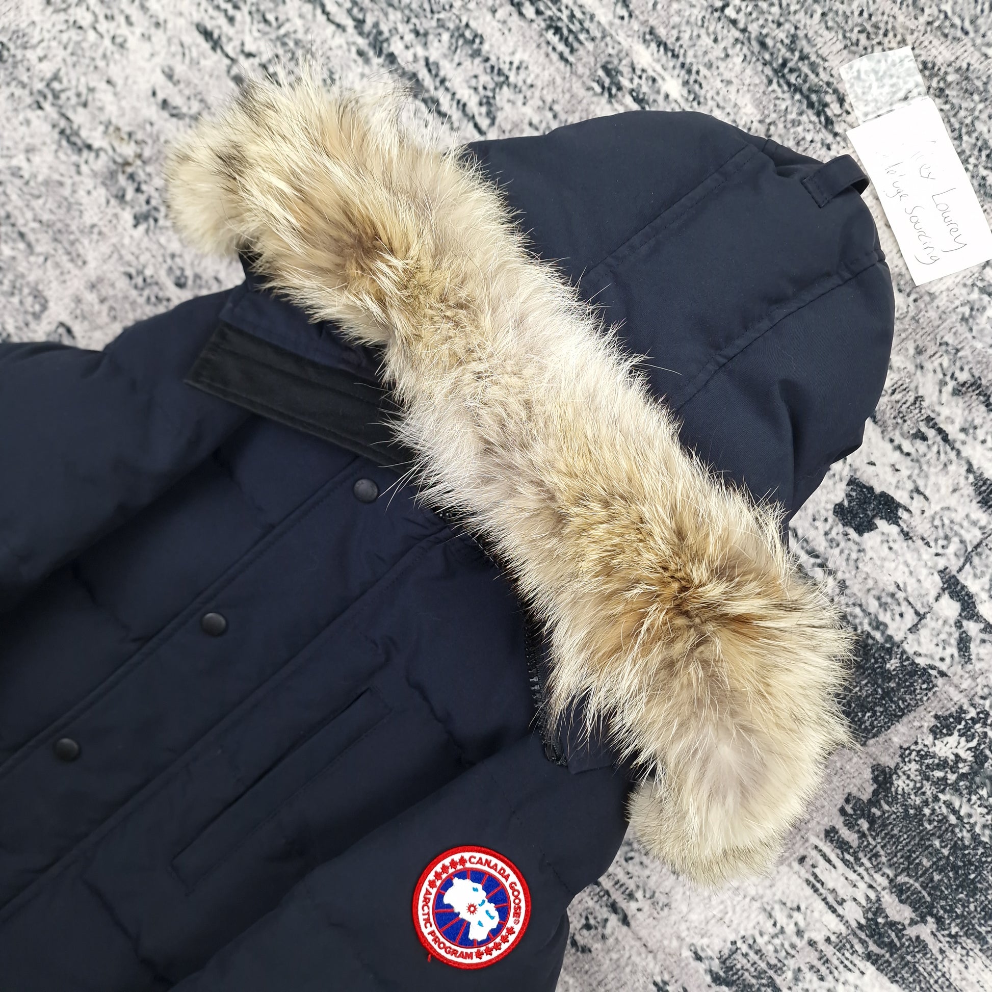 Close-up side view of Canada Goose Carson Parka showing authentic coyote fur hood trim and iconic Canada Goose Arctic Program badge, navy colorway 3805MA Small