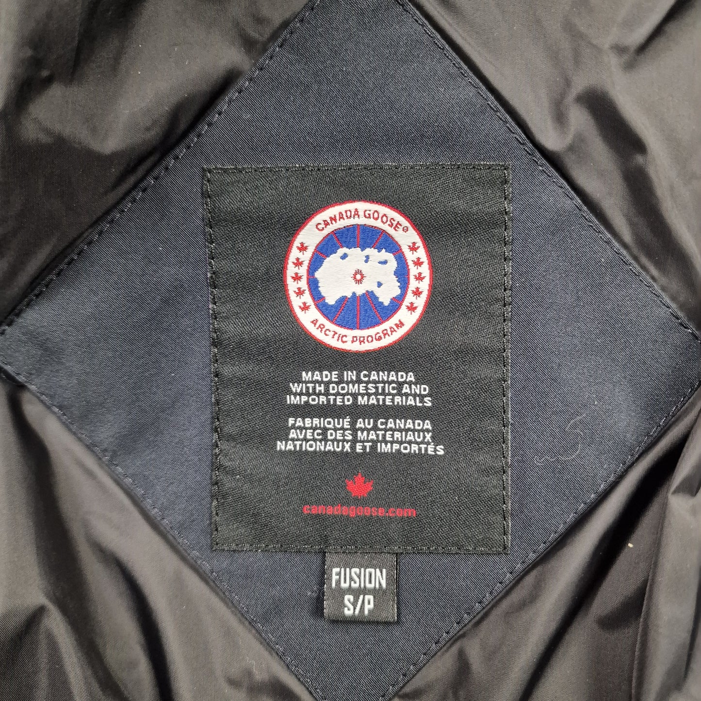 Close-up of Canada Goose necktag label inside Carson Parka 3805MA, showing authentic branding and size Small details for men's navy winter jacket