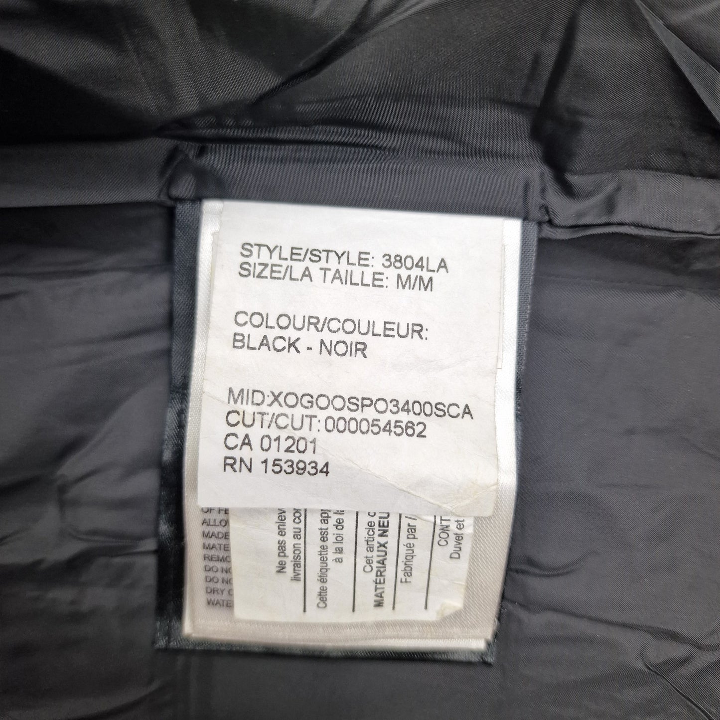 White care label washtag showing style code 3804LA, black color designation, and size Medium information for authentic Canada Goose Chelsea Parka women's winter jacket
