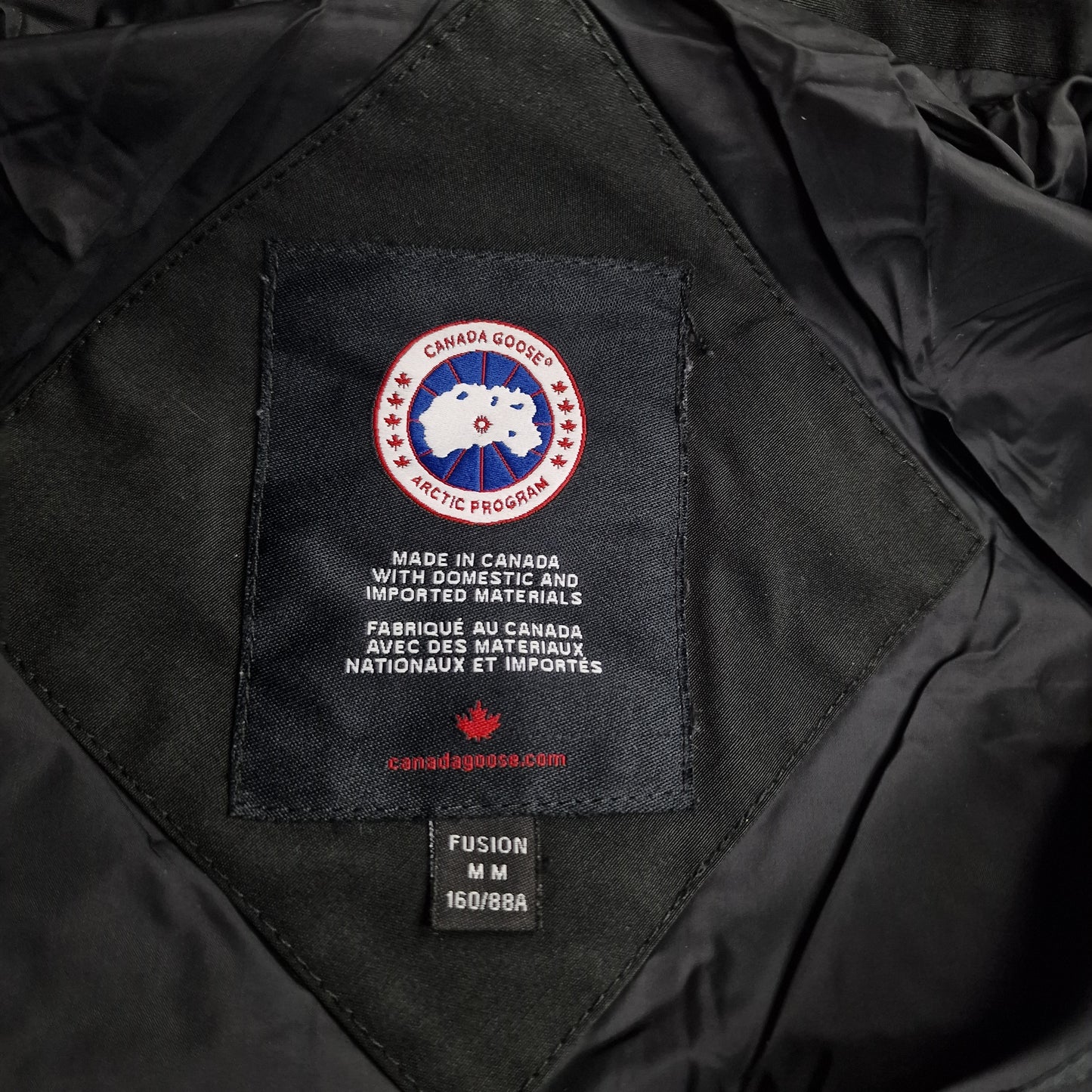 Close-up of Canada Goose necktag label inside Chelsea Parka 3804LA, showing authentic branding and size Medium details for women's black winter jacket