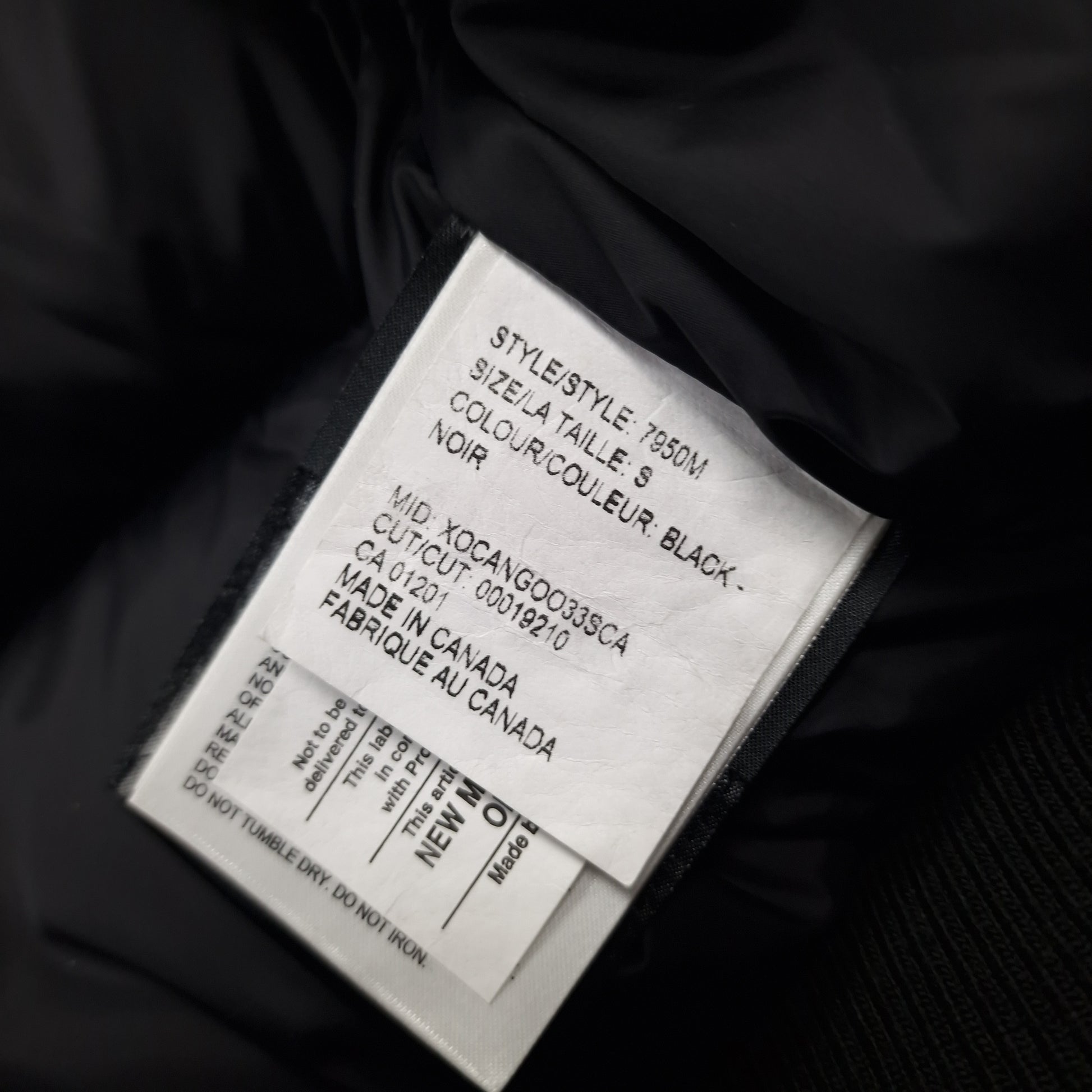 White care label washtag showing style code 7950M, black color designation, and size Small information for authentic Canada Goose Chilliwack Bomber men's jacket