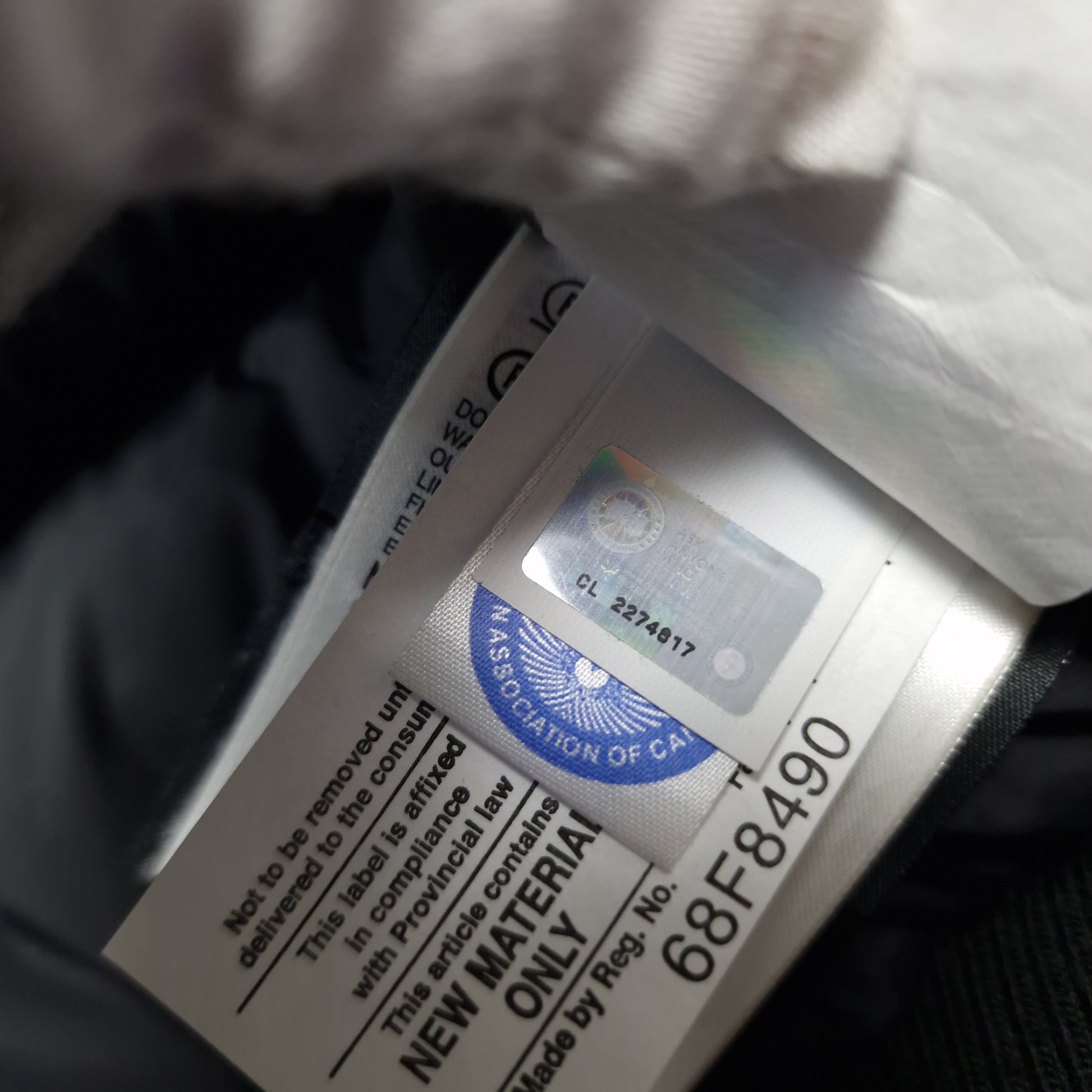 Close-up of Canada Goose authenticity hologram on Chilliwack Bomber 7950M, verification label confirming genuine men's Small black luxury bomber jacket