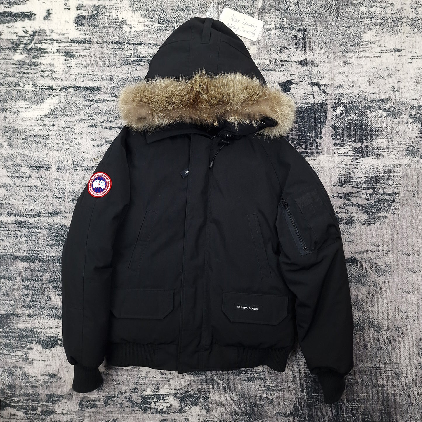 Front view of men's Canada Goose Chilliwack Bomber 7950M Small in black with coyote fur-trimmed hood, luxury bomber jacket photographed on styled background