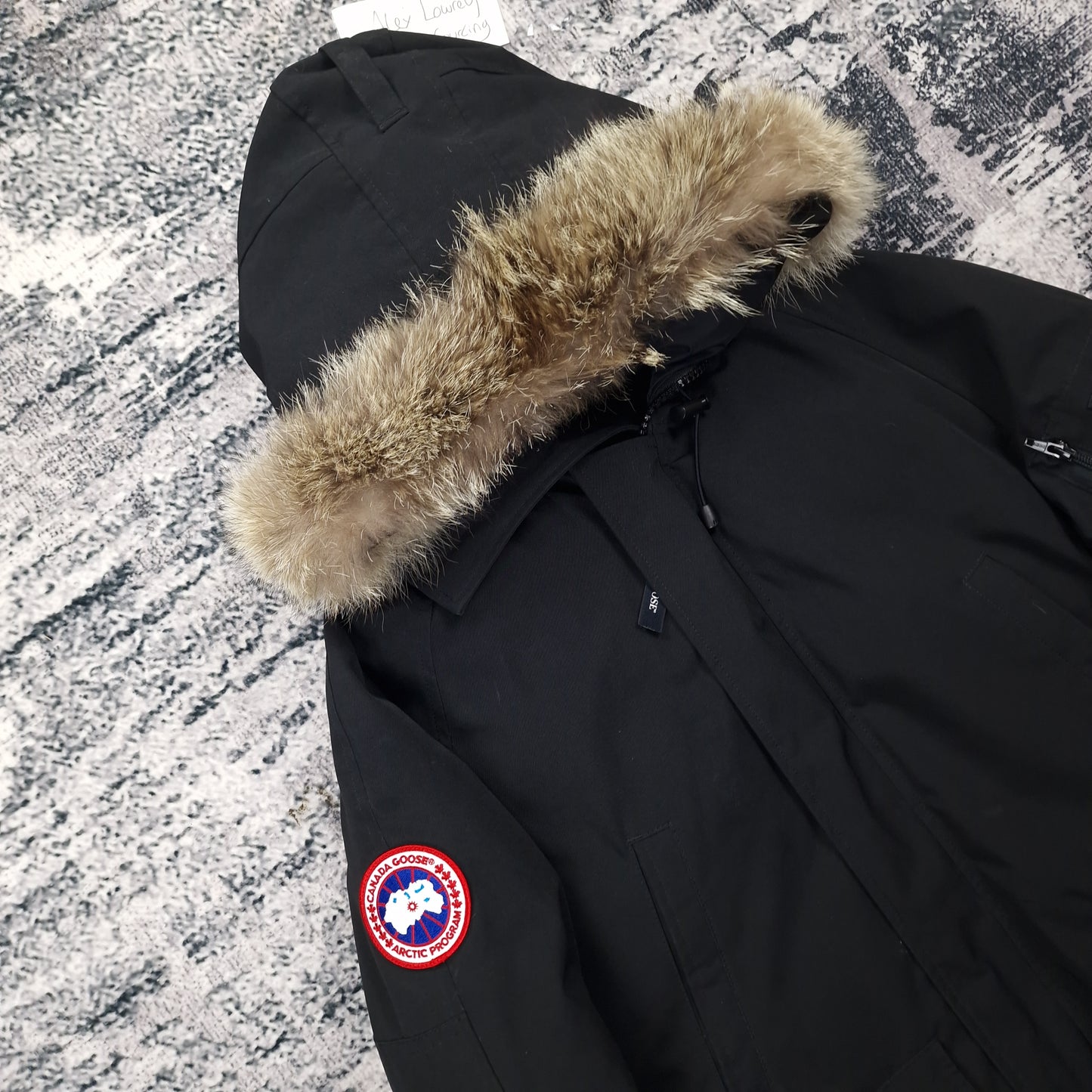 Close-up side view of Canada Goose Chilliwack Bomber showing authentic coyote fur hood trim and iconic Canada Goose Arctic Program badge, black colorway 7950M Small