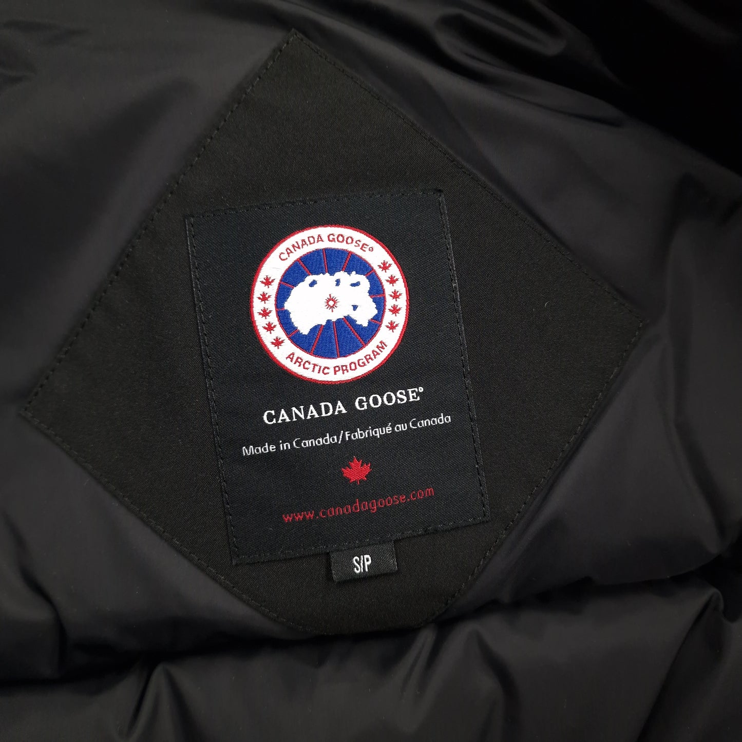 Close-up of Canada Goose necktag label inside Chilliwack Bomber 7950M, showing authentic branding and size Small details for men's black bomber jacket