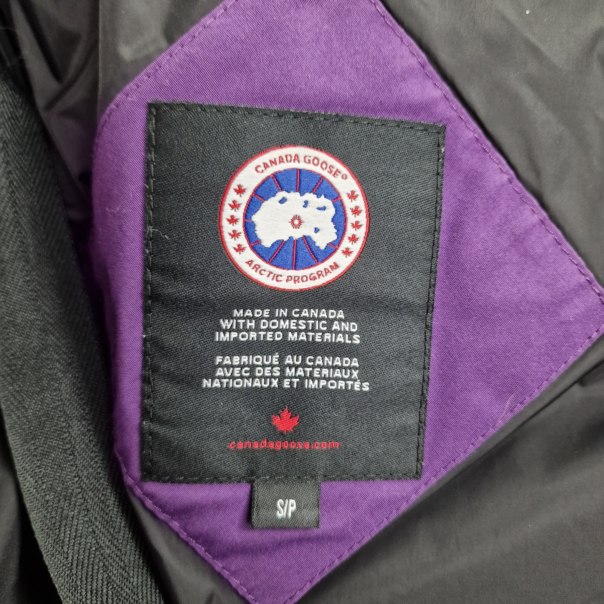 Close-up of Canada Goose necktag label inside Shelburne Parka 3802L, showing authentic branding and size details for women's Purple Arctic Disk rare colorway winter jacket