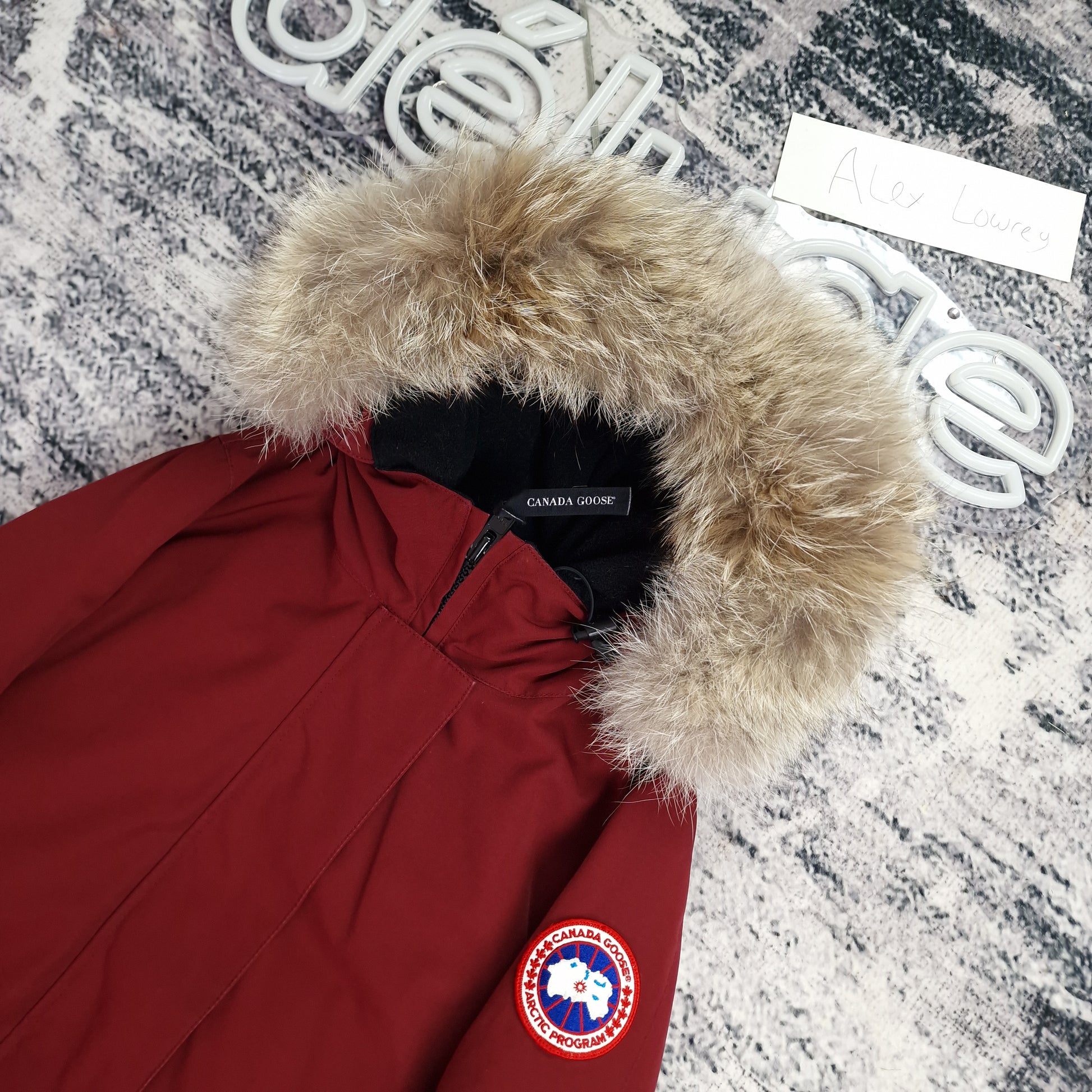 Close-up side view of Canada Goose Victoria Parka showing authentic coyote fur hood trim and iconic Canada Goose Arctic Program badge, Niagara Grape burgundy colorway size Small