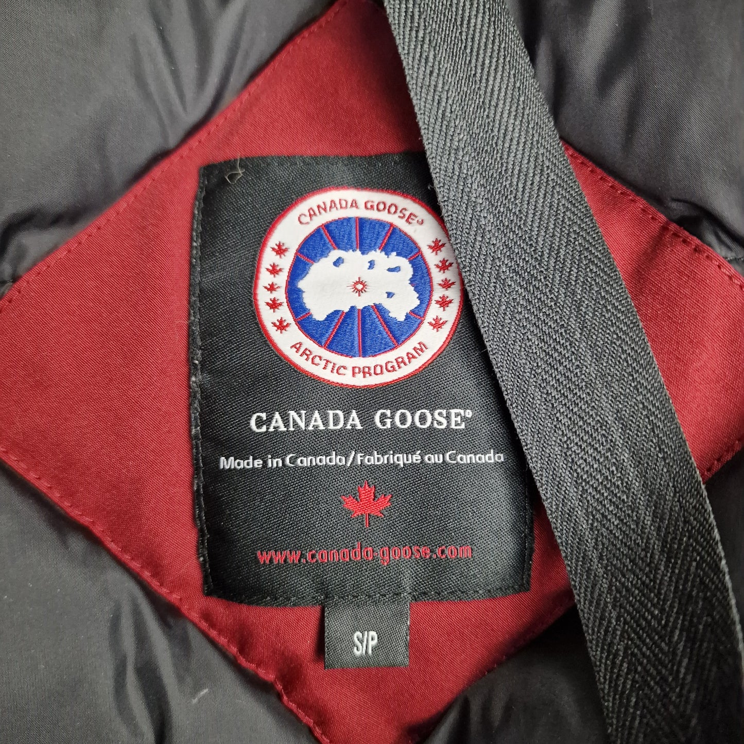 Close-up of Canada Goose necktag label inside Victoria Parka, showing authentic branding and size Small details for women's Niagara Grape burgundy winter jacket
