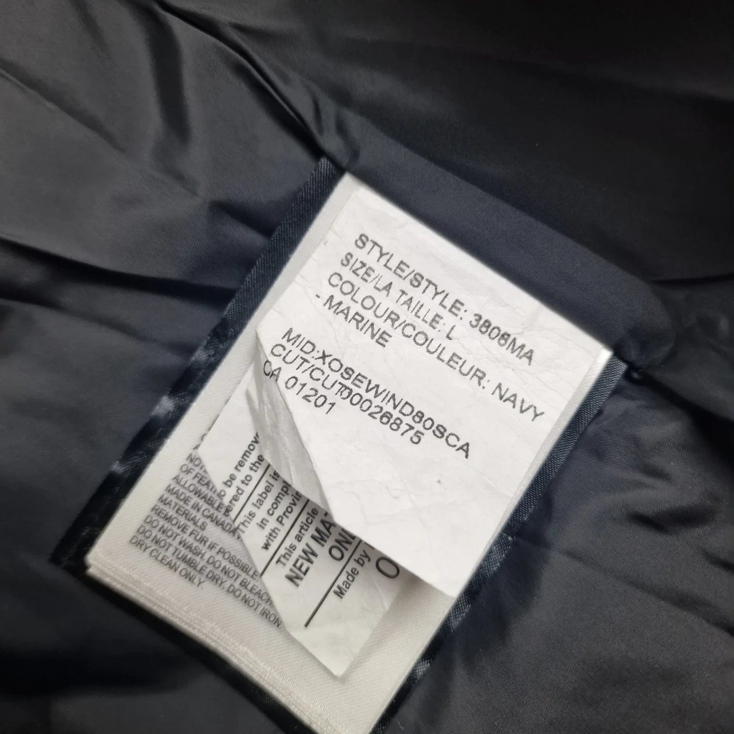White care label washtag showing style code 3808MA, navy color designation, and size Large information for authentic Canada Goose Wyndham Parka men's winter jacket