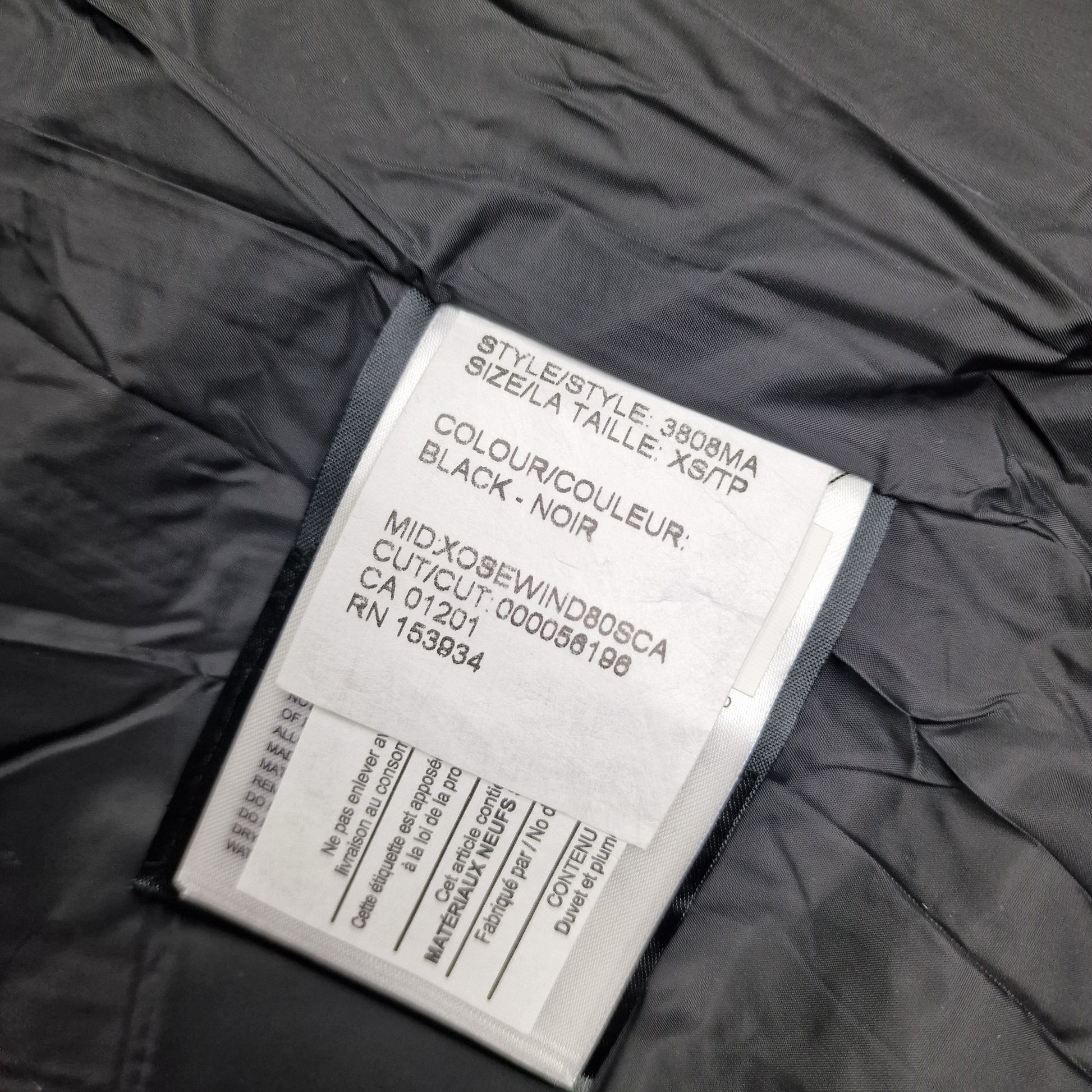 White care label washtag showing style code 3808MA, black color designation, and size XS information for authentic Canada Goose Wyndham Parka men's winter jacket
