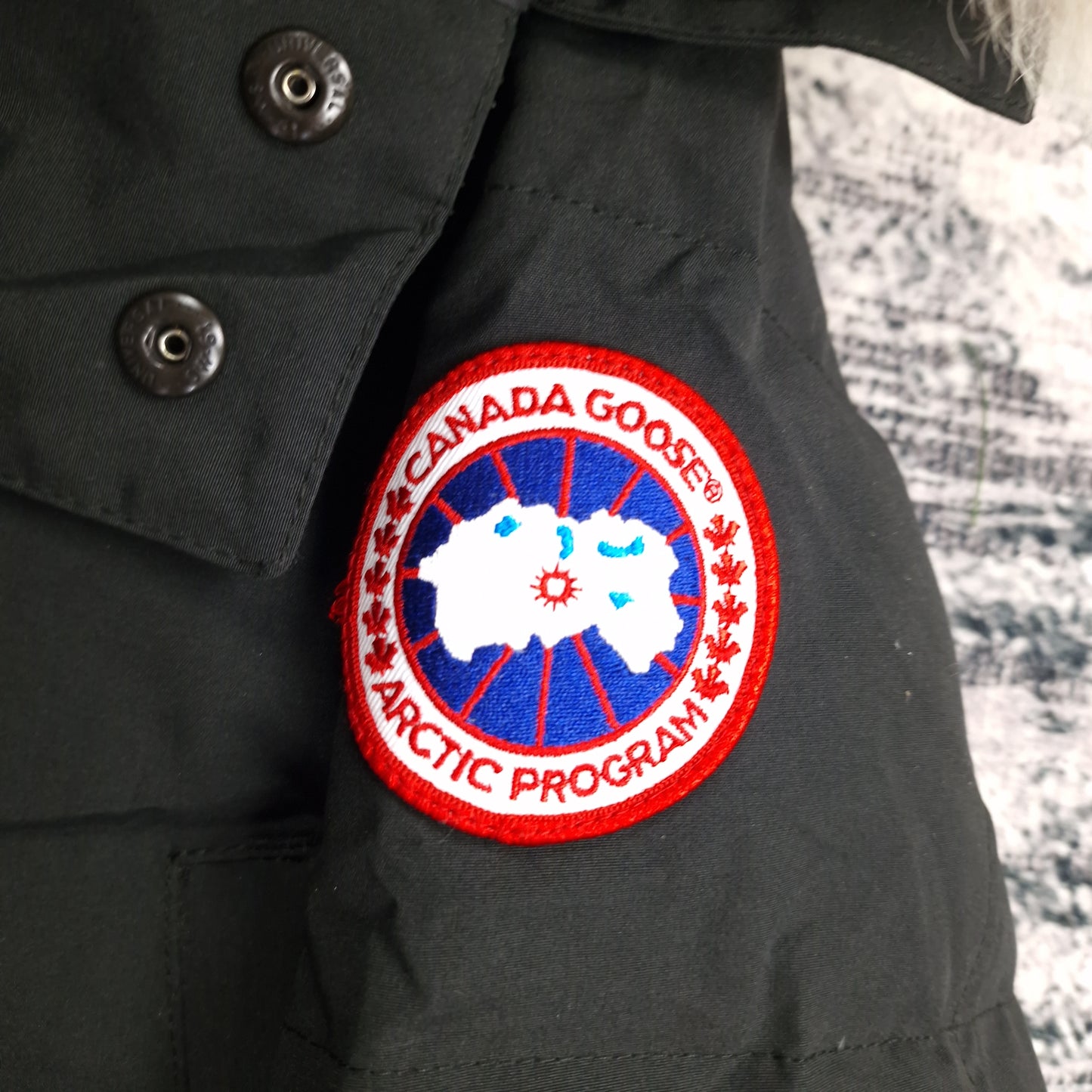 Close-up of authentic Canada Goose Arctic Program badge on Wyndham Parka 3808MA, black colorway XS, showing iconic logo patch detail on men's luxury winter jacket