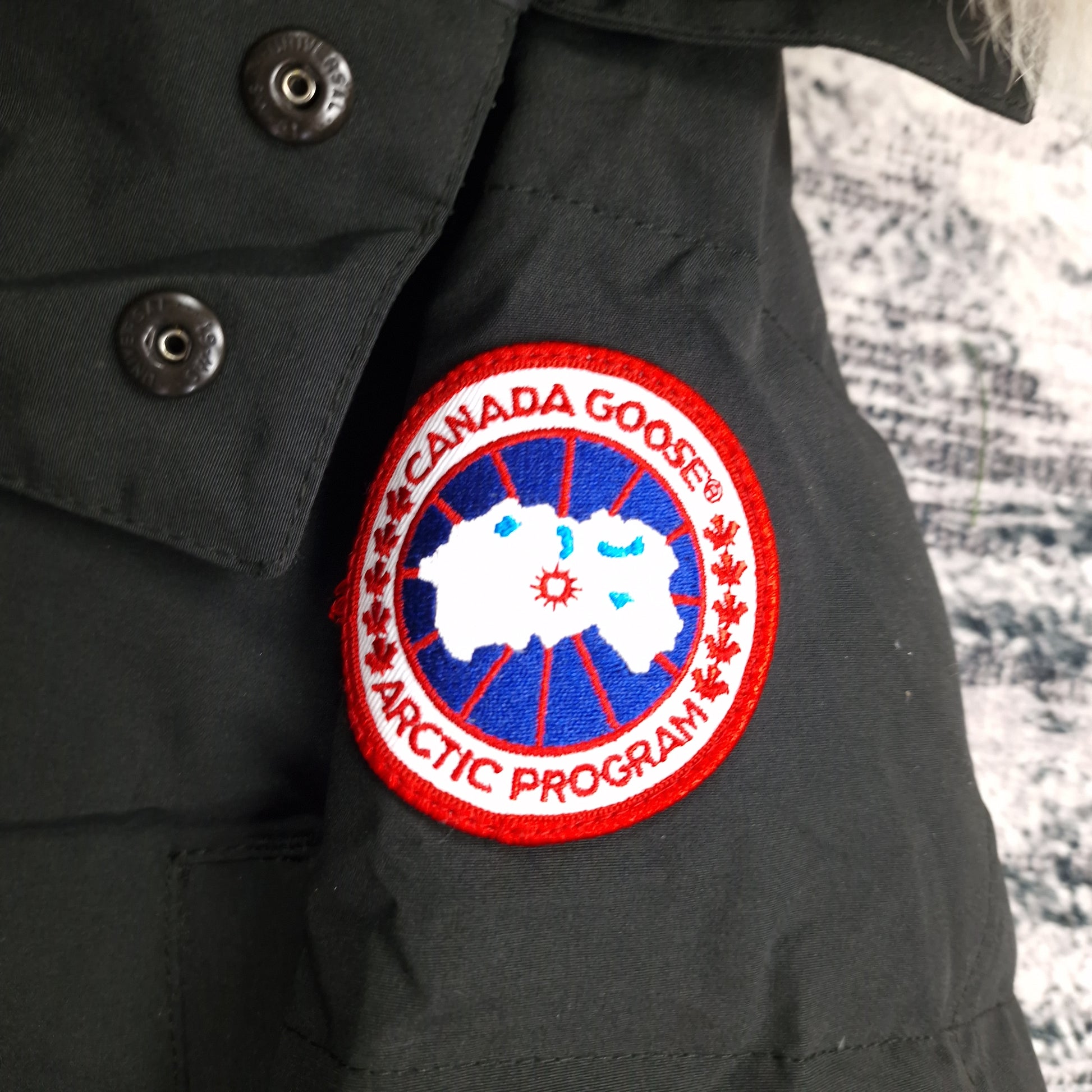 Close-up of authentic Canada Goose Arctic Program badge on Wyndham Parka 3808MA, black colorway XS, showing iconic logo patch detail on men's luxury winter jacket