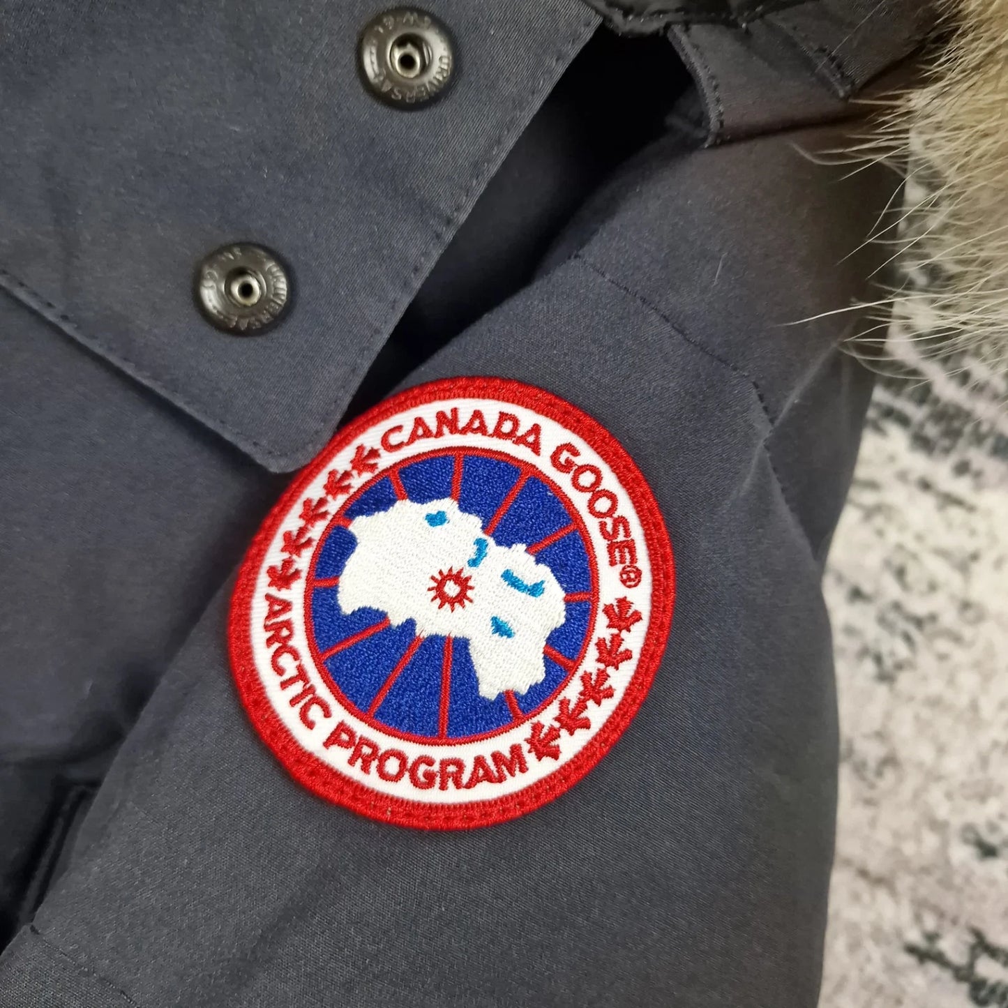 Close-up of authentic Canada Goose Arctic Program badge on Wyndham Parka 3808MA, navy colorway Large, showing iconic logo patch detail on men's luxury winter jacket
