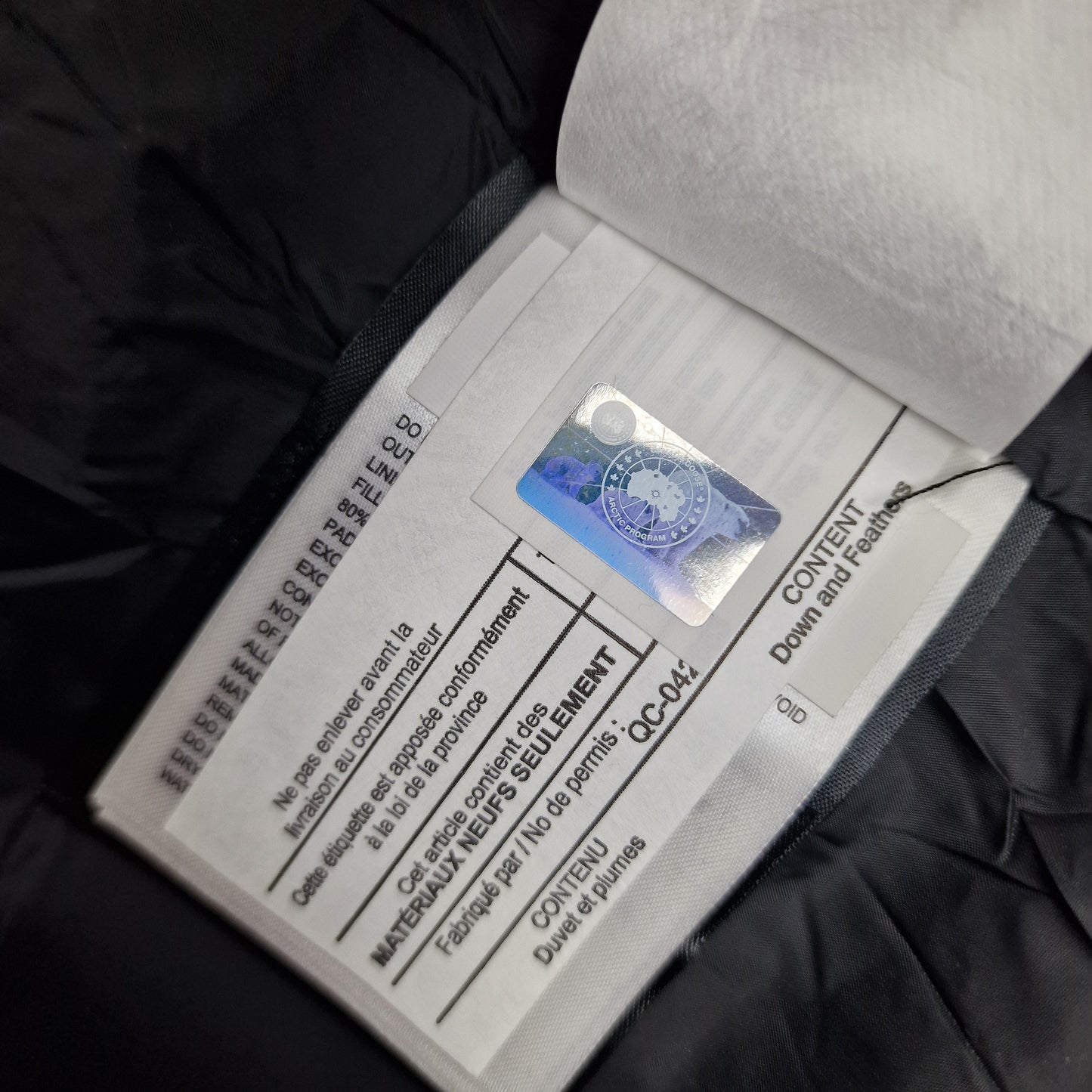 Close-up of Canada Goose authenticity hologram on Wyndham Parka 3808MA, verification label confirming genuine men's XS black luxury winter coat