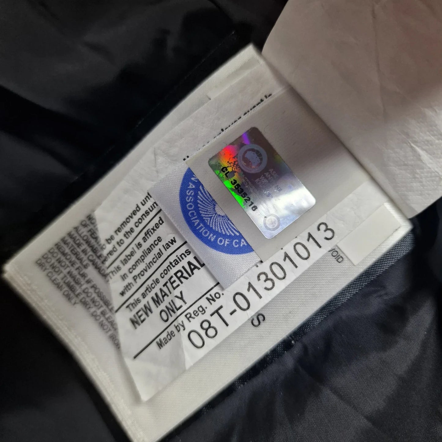 Close-up of Canada Goose authenticity hologram on Wyndham Parka 3808MA, verification label confirming genuine men's Large navy luxury winter coat