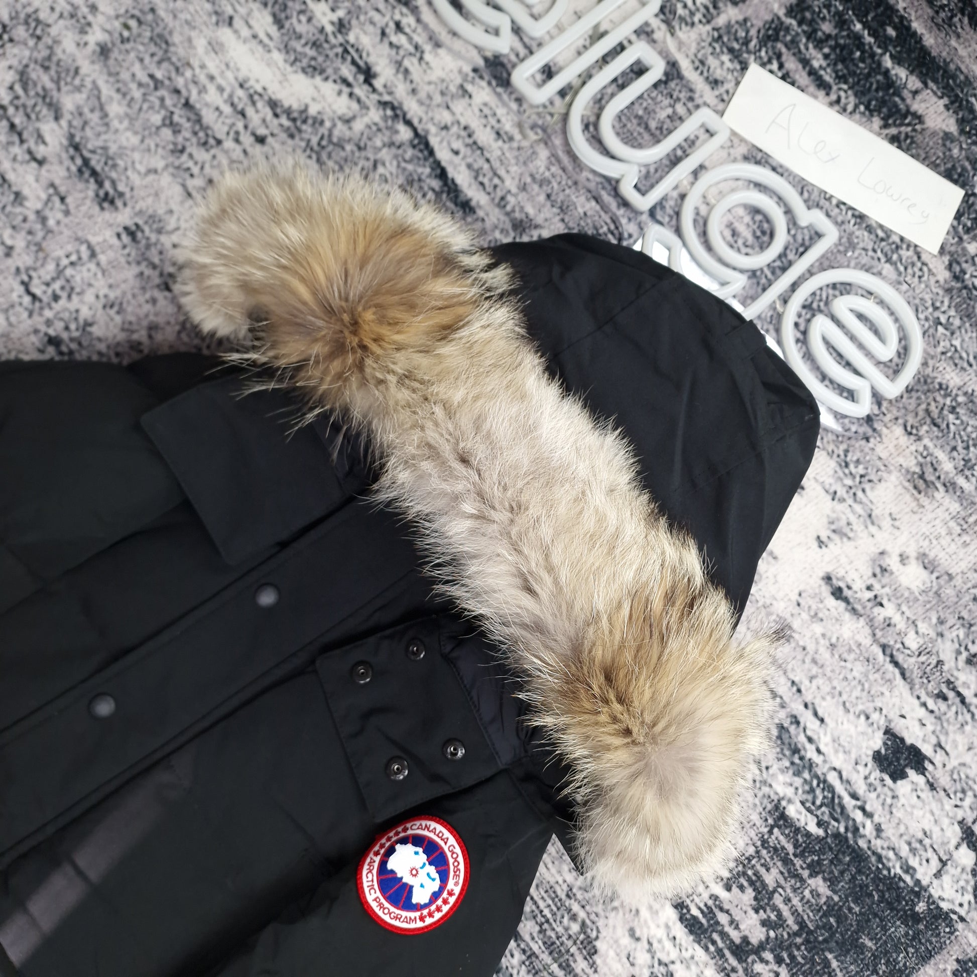 Close-up side view of Canada Goose Wyndham Parka showing authentic coyote fur hood trim and iconic Canada Goose Arctic Program badge, black colorway 3808MA XS