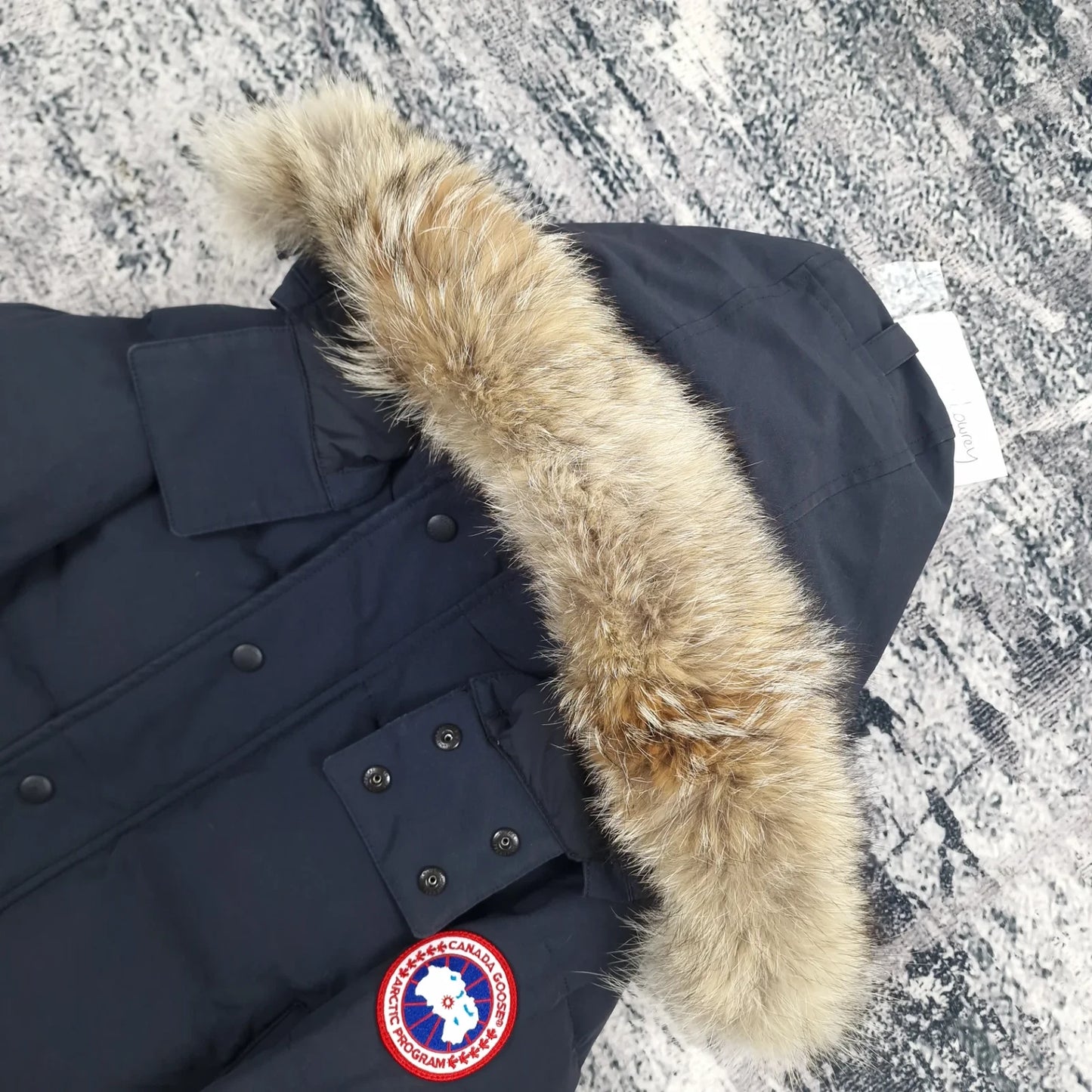 Close-up side view of Canada Goose Wyndham Parka showing authentic coyote fur hood trim and iconic Canada Goose Arctic Program badge, navy colorway 3808MA Large