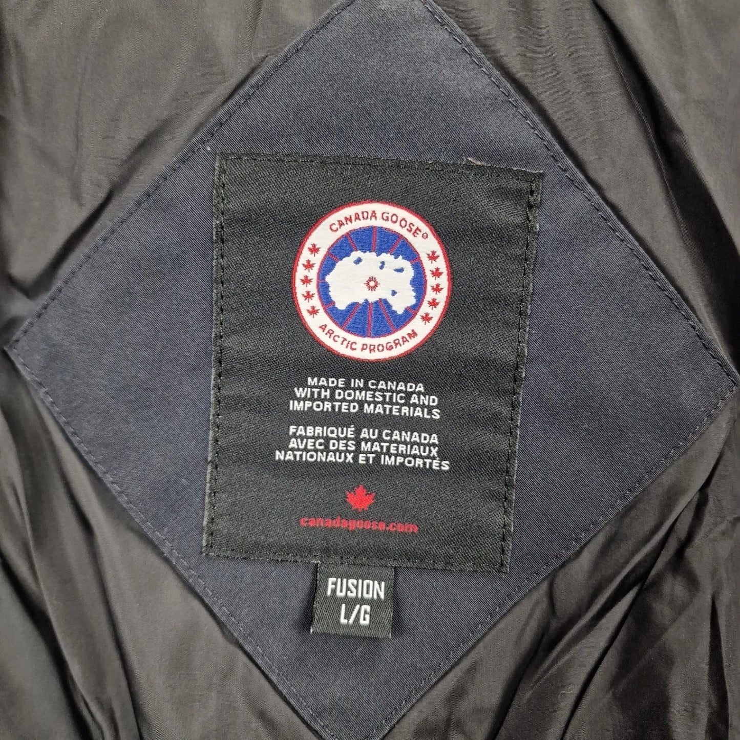 Close-up of Canada Goose necktag label inside Wyndham Parka 3808MA, showing authentic branding and size Large details for men's navy winter jacket