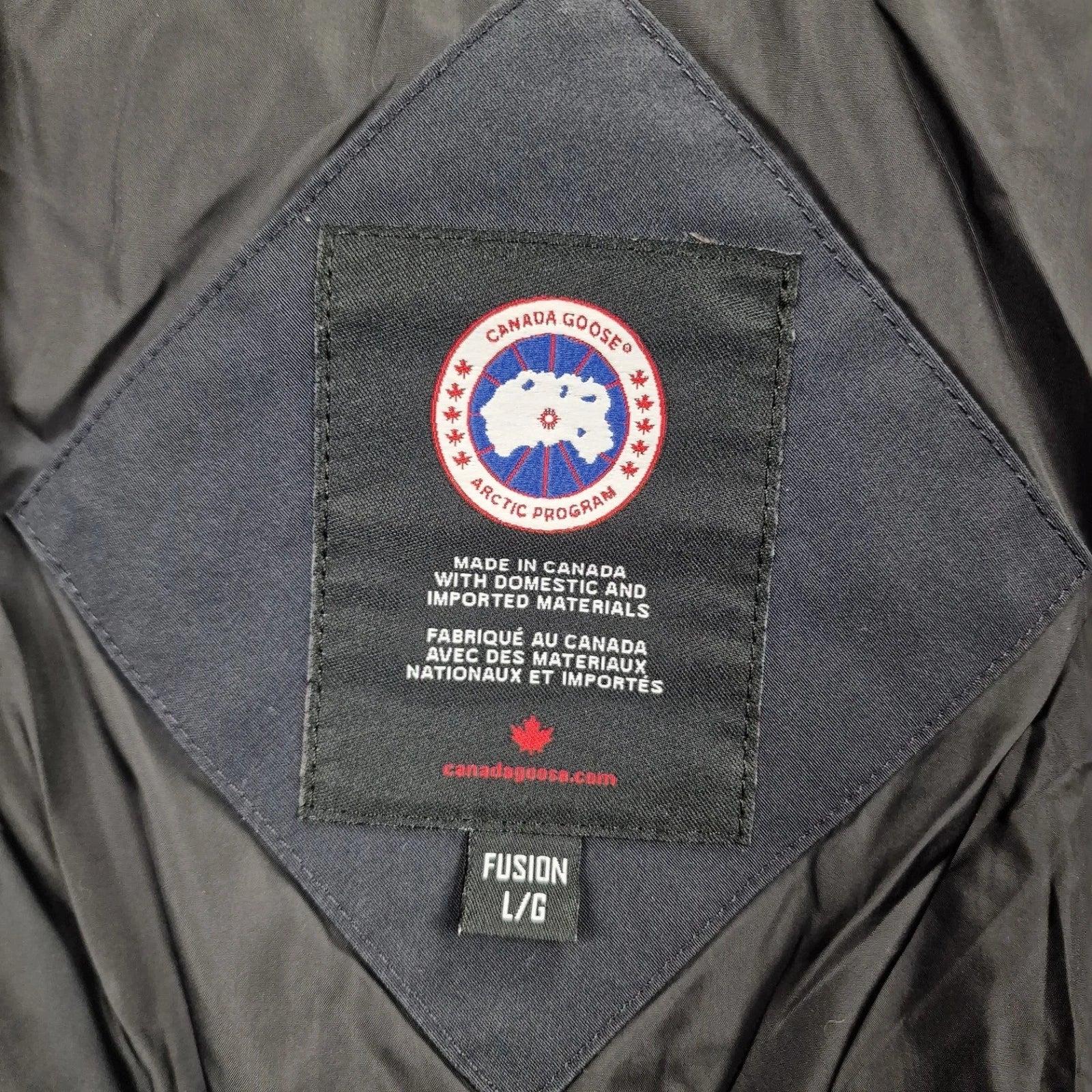 Close-up of Canada Goose necktag label inside Wyndham Parka 3808MA, showing authentic branding and size Large details for men's navy winter jacket
