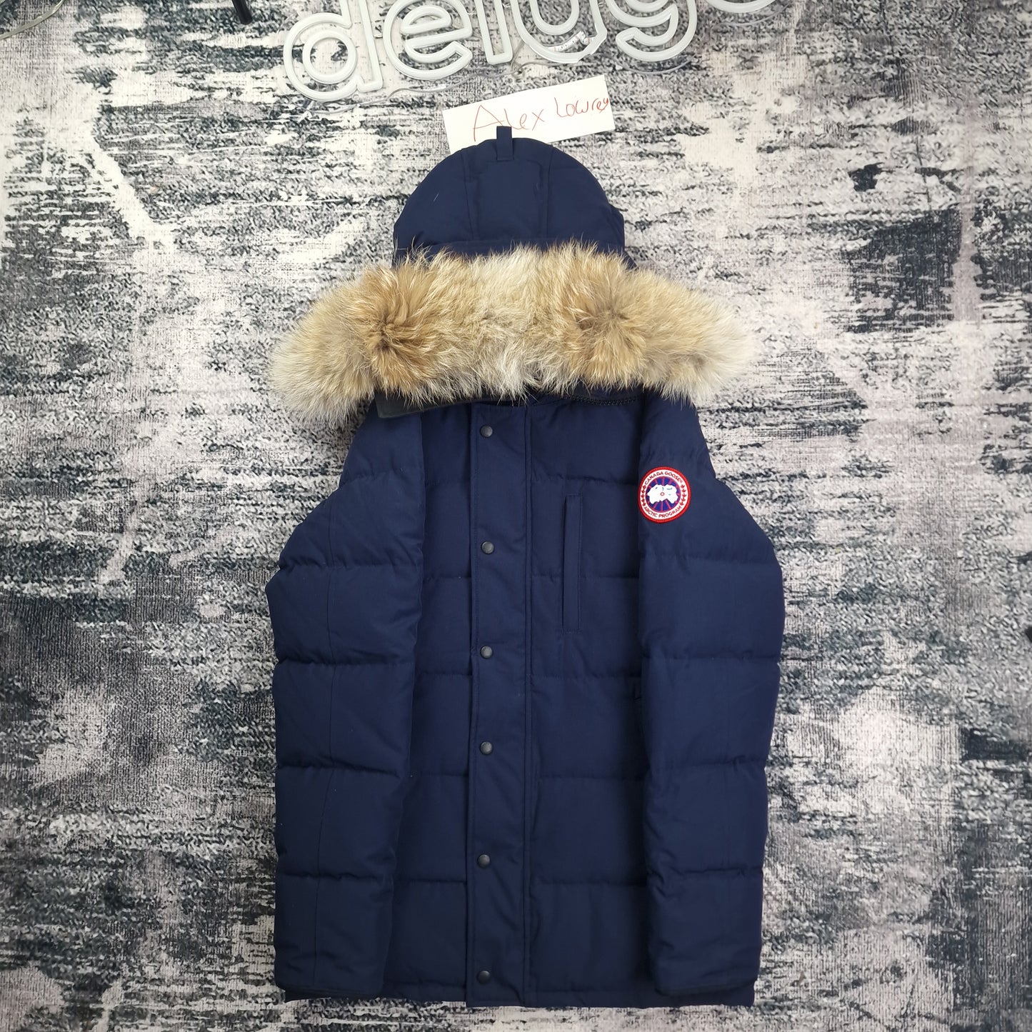 Front flat lay of Canada Goose Carson Parka 3805MA men's medium with coyote fur hood trim, chest pockets, and Arctic Program badge