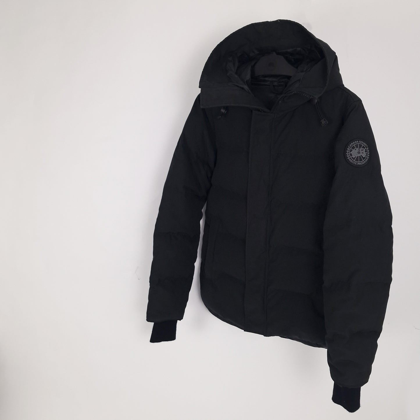 Angled view of black Canada Goose Macmillan Black Label Parka men's medium showing ribbed cuffs and sleek silhouette