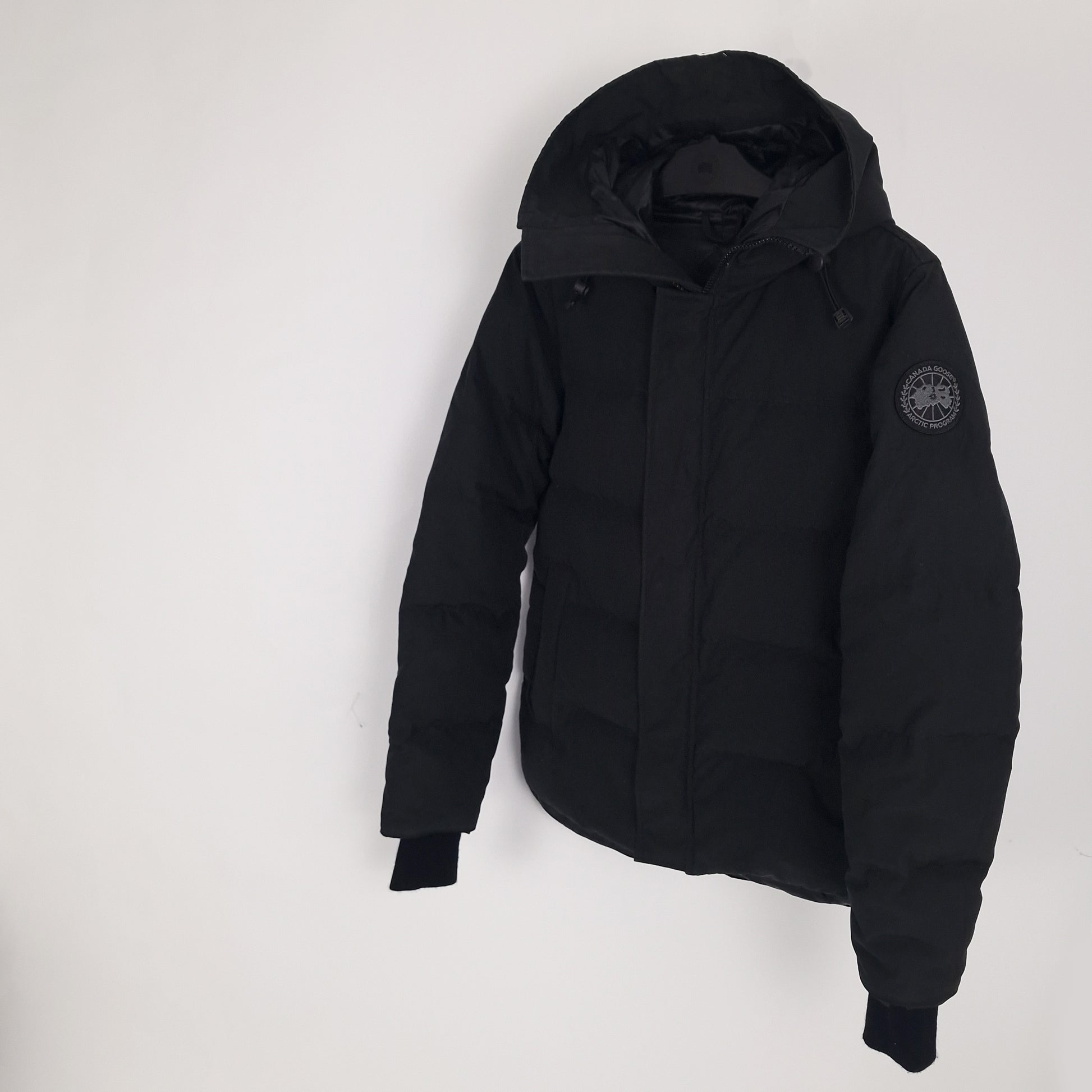 Angled view of black Canada Goose Macmillan Black Label Parka men's medium showing ribbed cuffs and sleek silhouette
