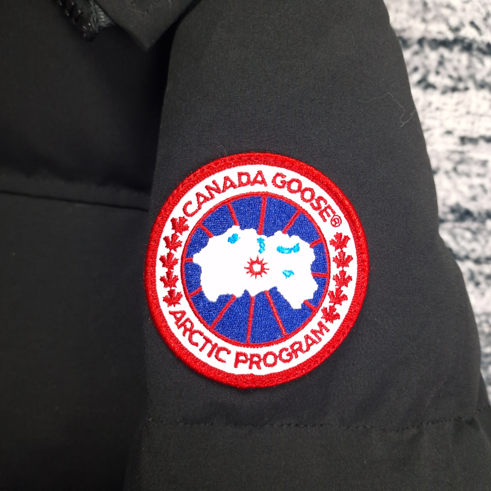 Detailed close-up of authentic Canada Goose Arctic Program patch on black Macmillan Parka 3804MA men's large sleeve
