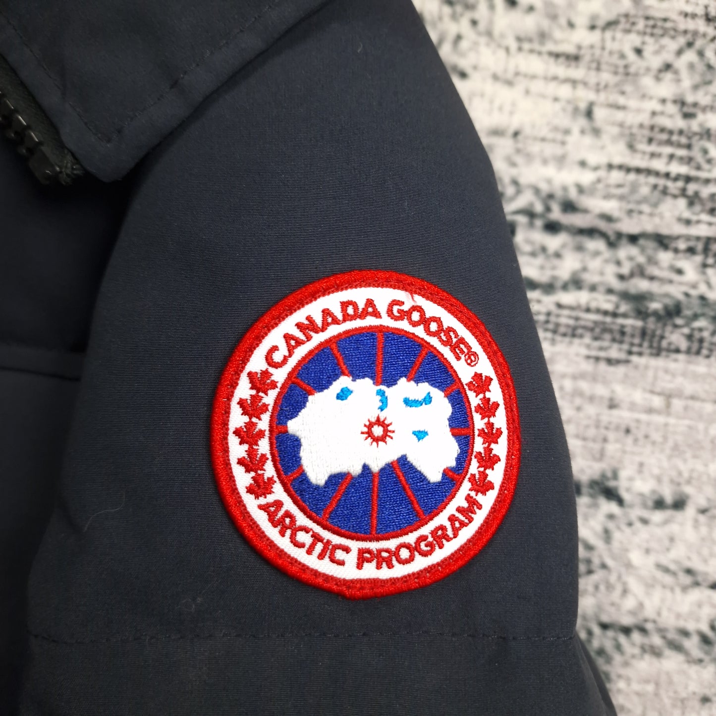 Detailed close-up of authentic Canada Goose Arctic Program patch on navy Macmillan Parka 3804M men's extra small sleeve