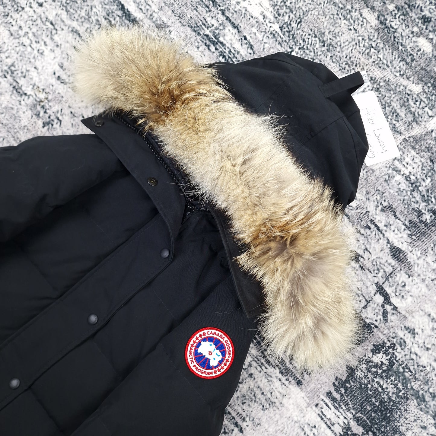 Close-up flat lay of Canada Goose Shelburne Parka 3802L showing luxurious coyote fur hood trim and Arctic Program badge
