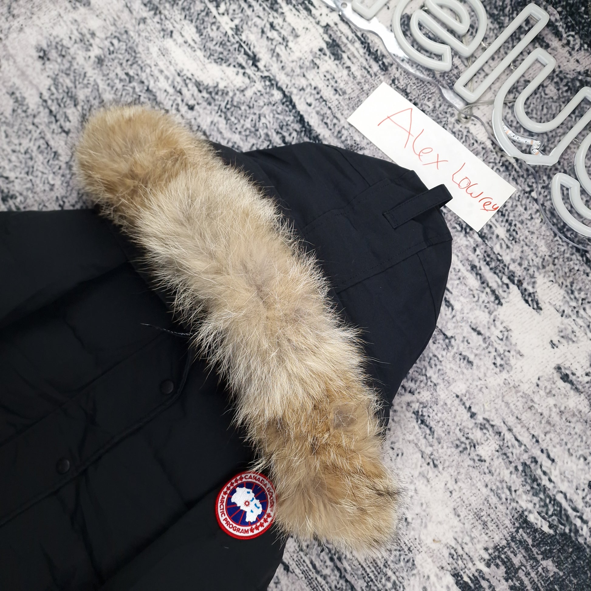 Close-up flat lay of Canada Goose Shelburne Parka 3802LA showing coyote fur hood trim and Arctic Program disc badge
